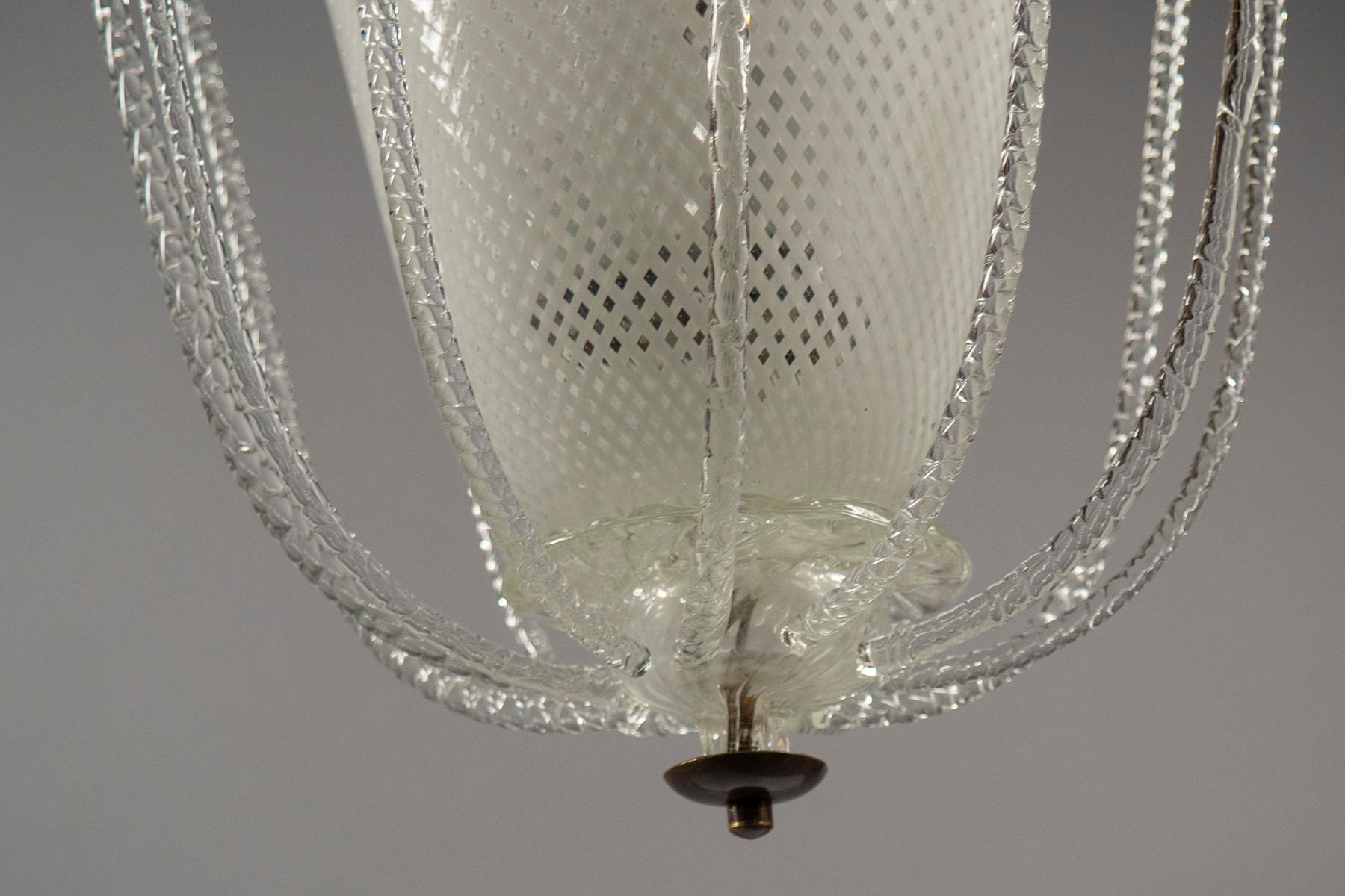Conical reticello glass body, surrounded by twisted glass rods, suspended from a glass stem with reticello canopy.
  