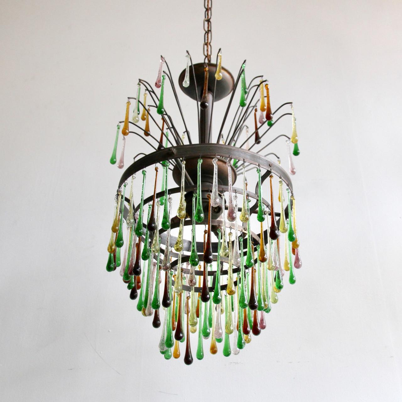 This waterfall chandelier frame originates from early 1900s, France. It has been dressed in contemporary and vintage colored glass teardrops in greens, rich browns, purple with some clear. This chandelier is a unique statement centerpiece which is