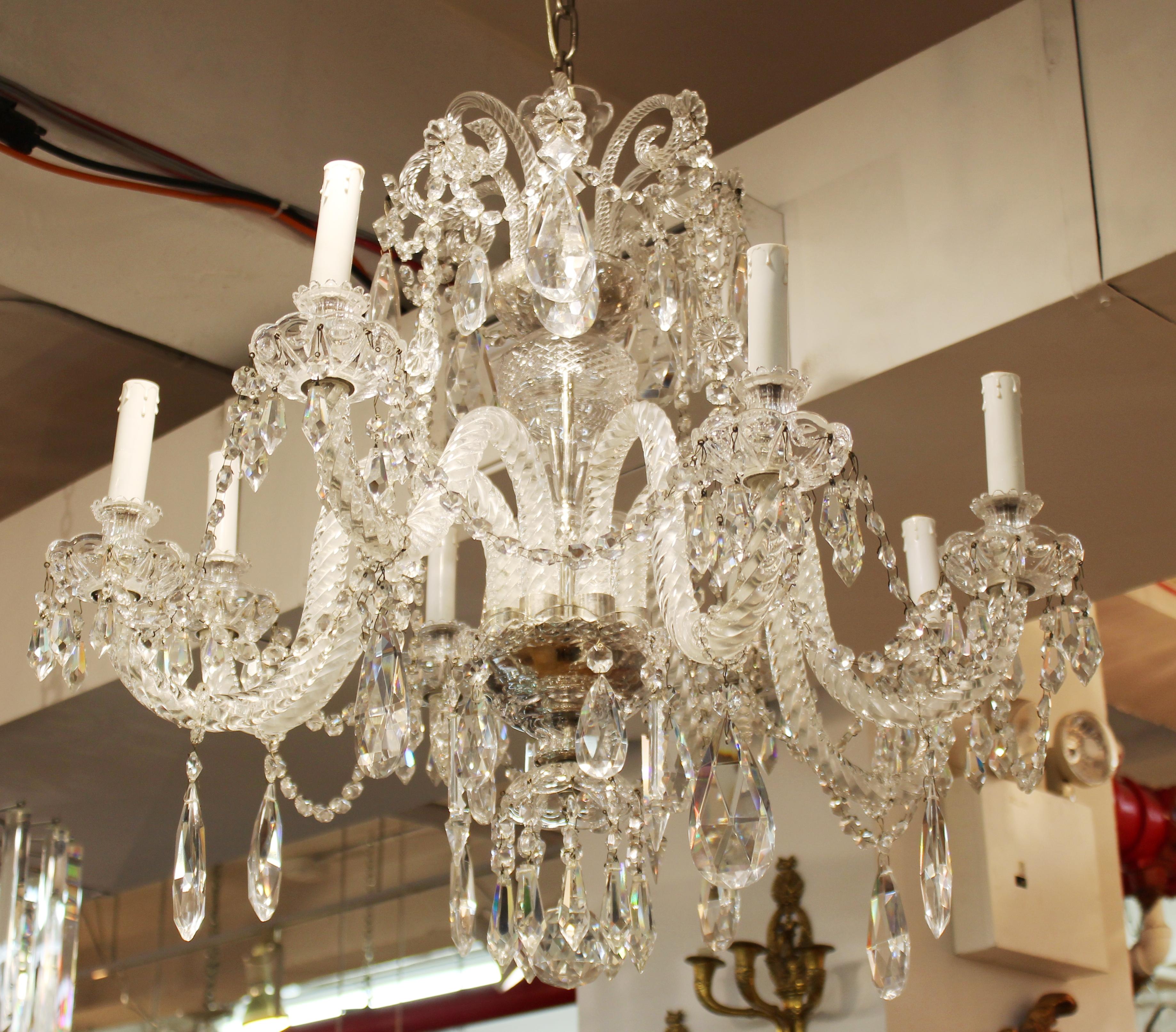 Neoclassical style crystal chandelier by Spanish maker Martinez y Ortz. The piece has eight light arms and a multitude of decorative crystal droplets and is signed. In great vintage condition with age-appropriate wear and use. 