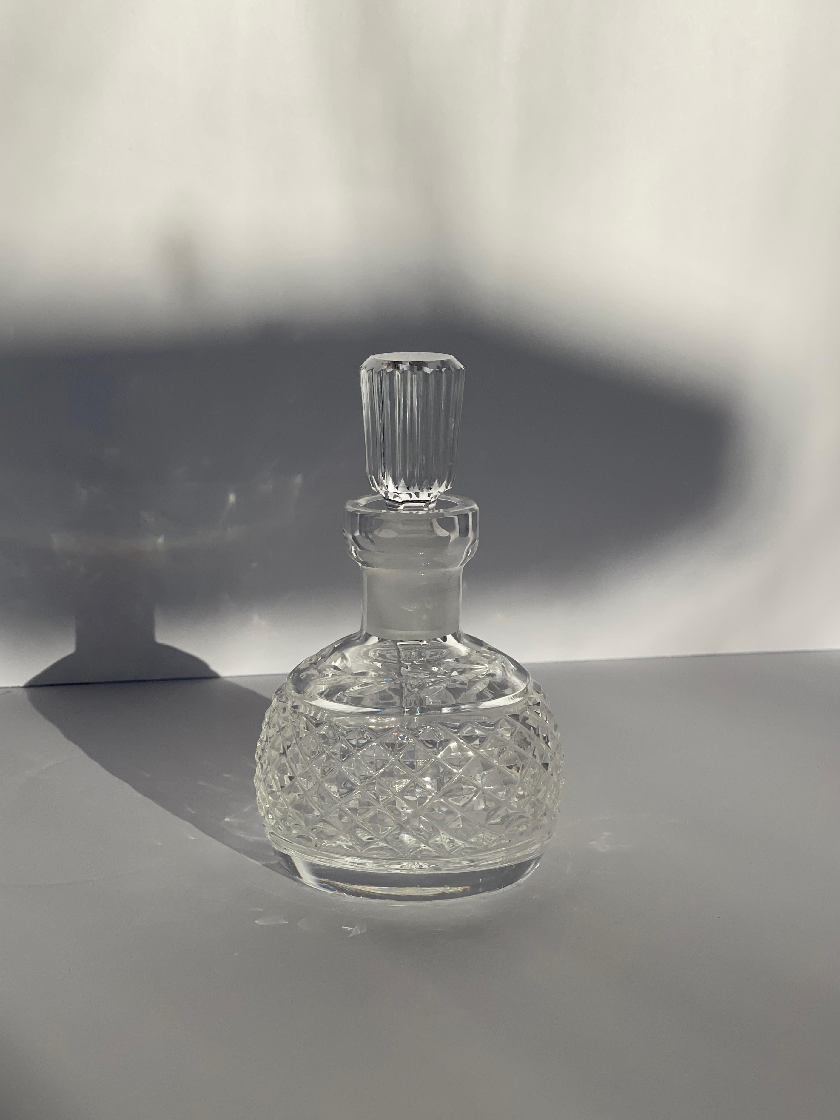 Exemple exquis de cristal fin irlandais, ce flacon de parfum à facettes de Waterford incarne l'élégance, le savoir-faire et la beauté intemporelle. Probablement produite entre 1920 et 1950, la bouteille présente la brillance et la précision de coupe