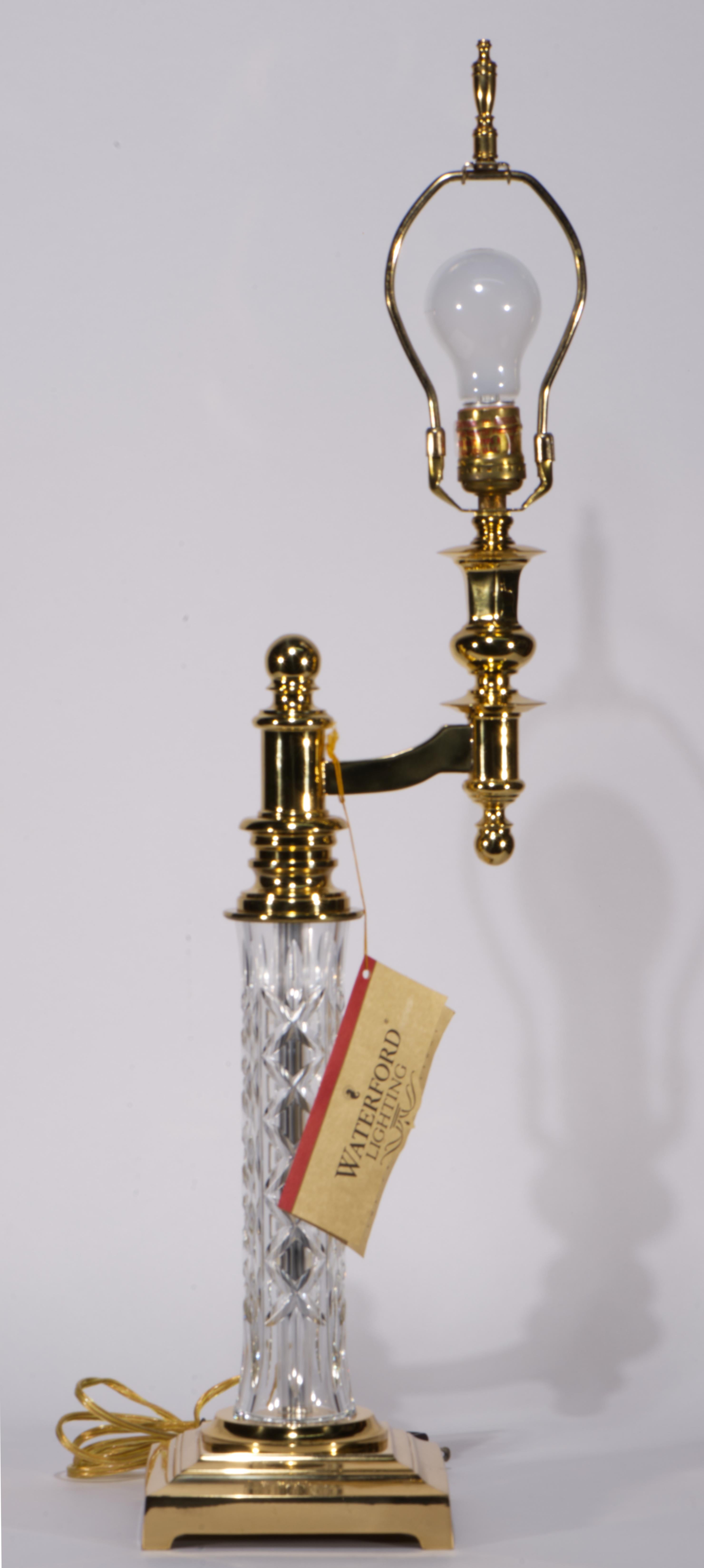 Vintage table lamp features sculptural cut crystal base with brass base and topper with an arm. Elongated cylinder-shaped crystal body is decorated with parallel bands of large cut diamond designs in Kinsale (or Killarney) pattern, accentuating the