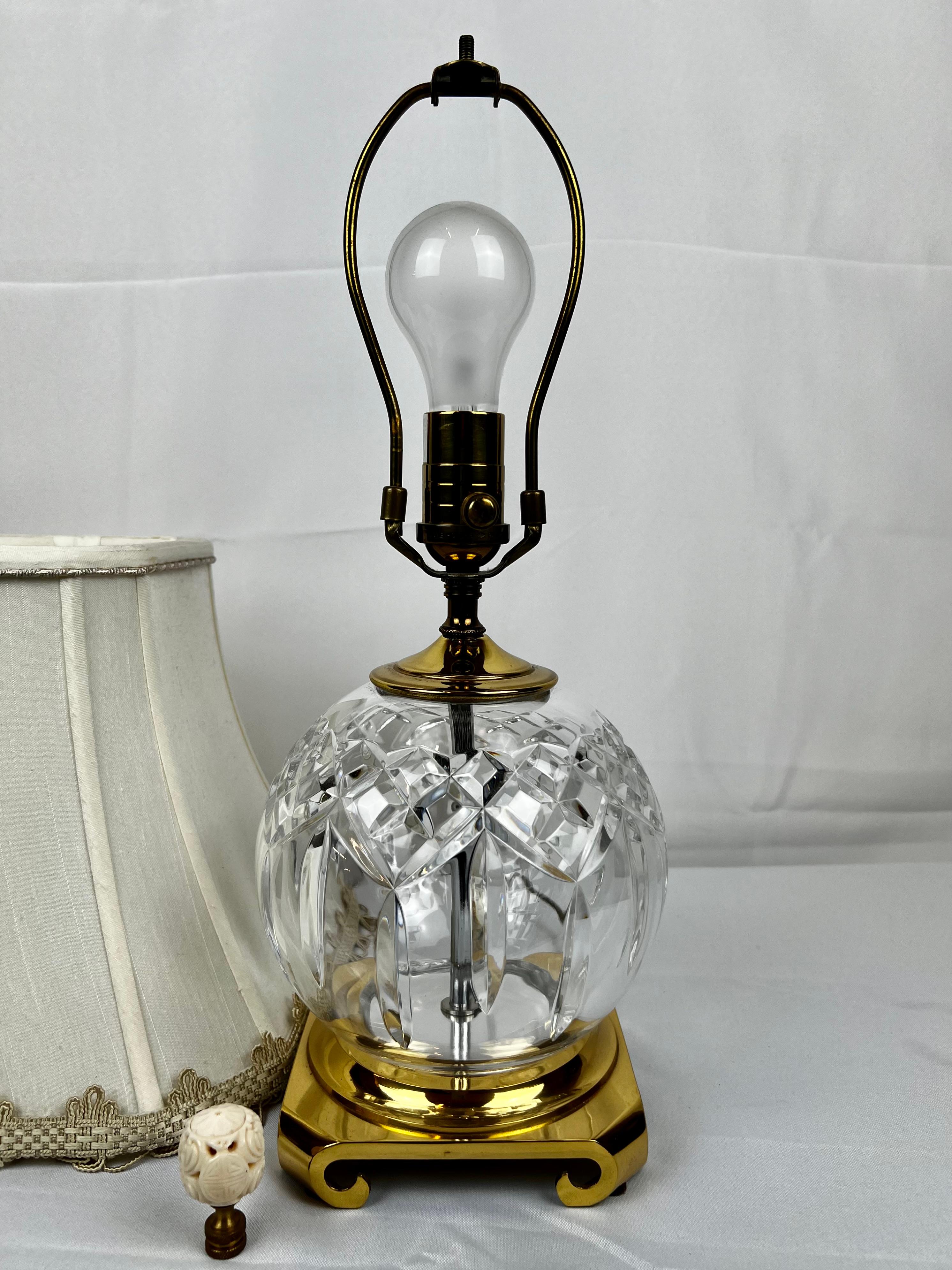 “Lismore” pattern cut crystal round shaped lamp marked Waterford on the socket.   It has an off white shade with customized trim by Blanche Fields of Boston.  The brass base is marked Crescent Brass MFG.  FYI I included a photo in a lit room with