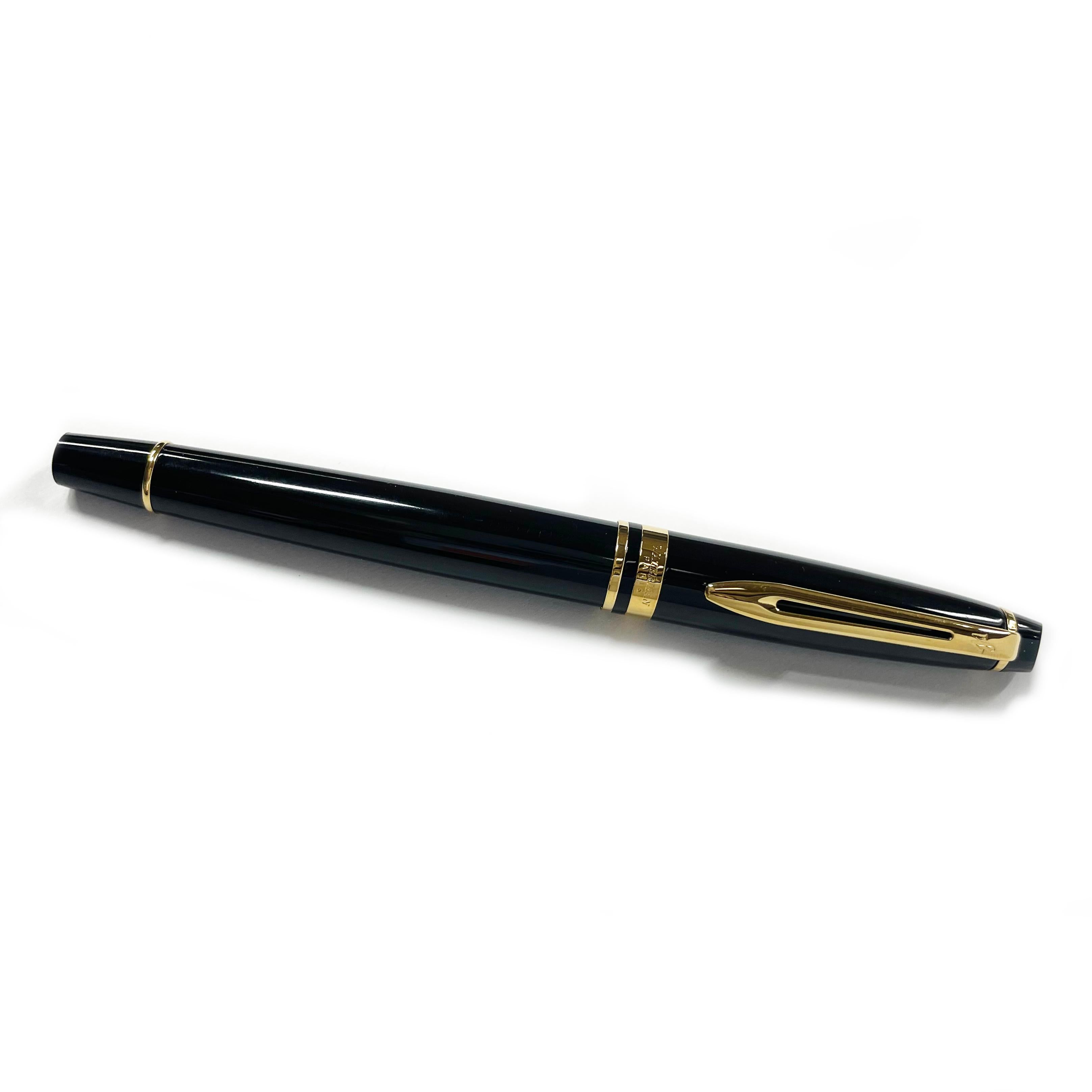 Waterman Gold Plated Fountain Pen. The Waterman Expert fountain pen has a gloss lacquer finish with 23 karat gold plated trim. The pen has a cigar-shaped barrel, a beveled button cap, and a medium nib. The pen is marked with the Waterman logo on the