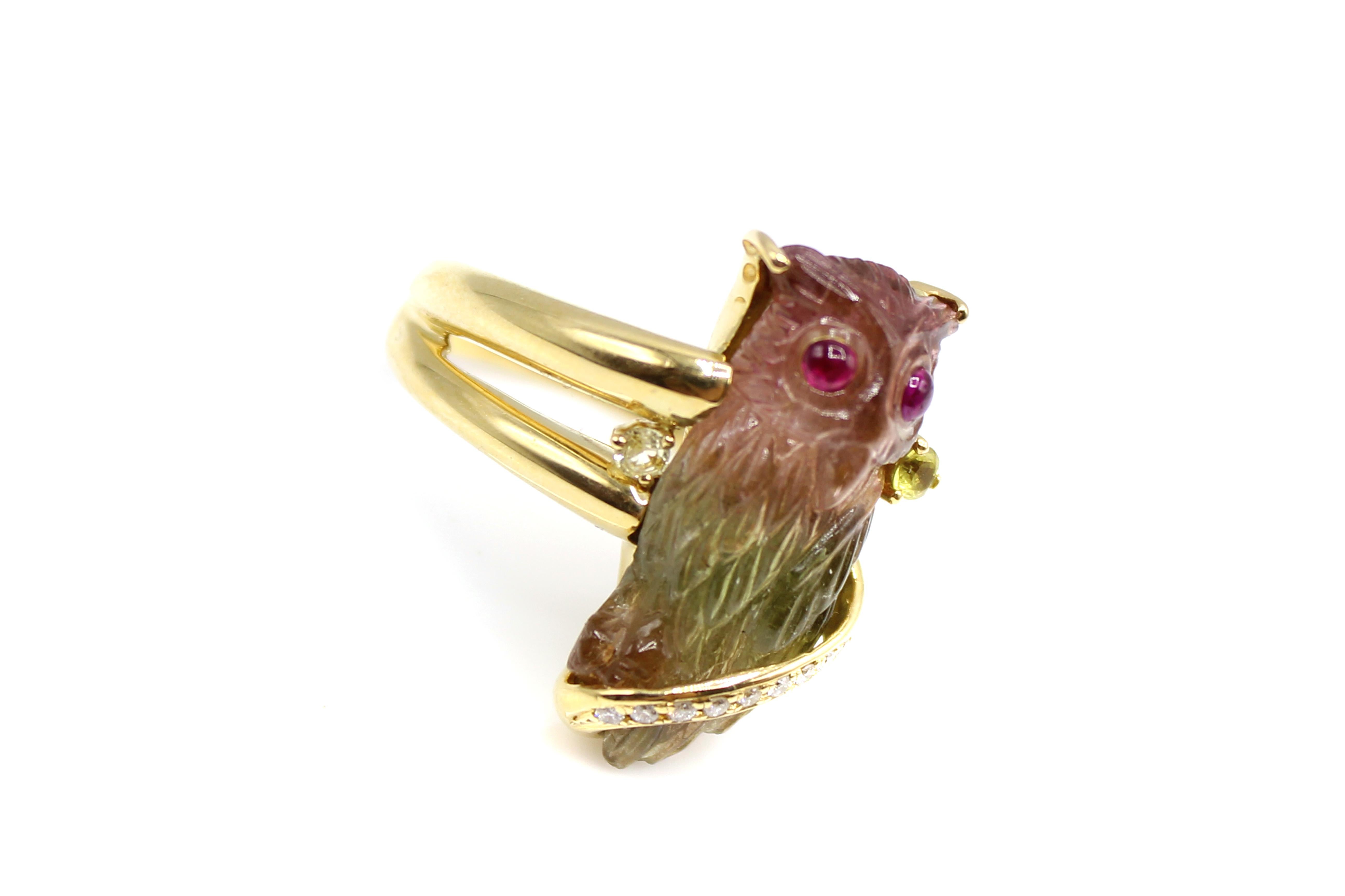 This interesting and unique ring is centrally set with a bold colorful watermelon tourmaline carved owl. The asymmetrical split shank securely holds the tourmaline owl in place, with one side of the gold lapping over the tourmaline with 9 small