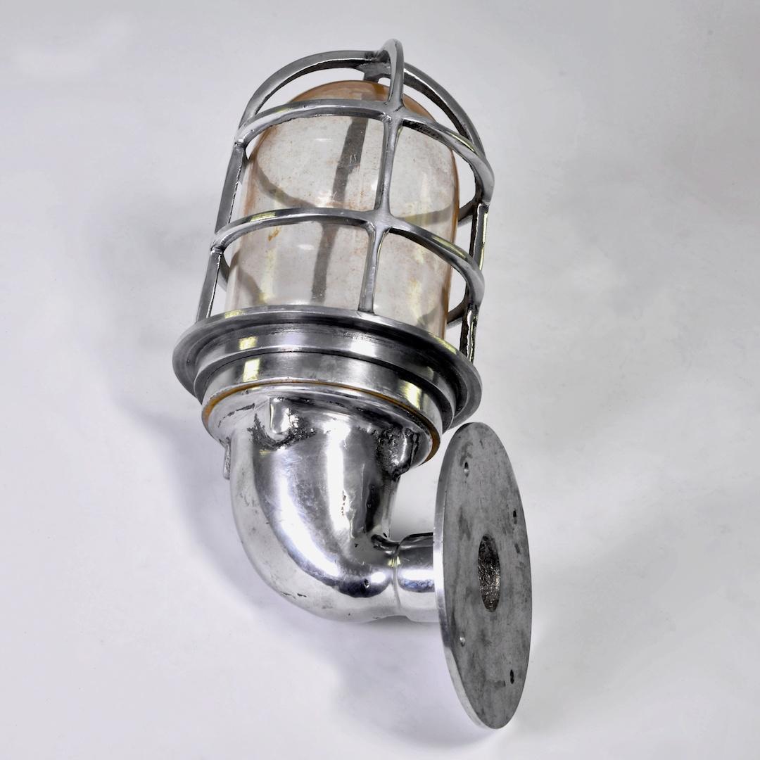 1960s polished cast aluminum wall light with a cage protection and a glass shade. Beautifully made, in a thick aluminum giving a superb sculptural aspect. With this Classic and timeless design this wall light is beautiful on its own and as a series