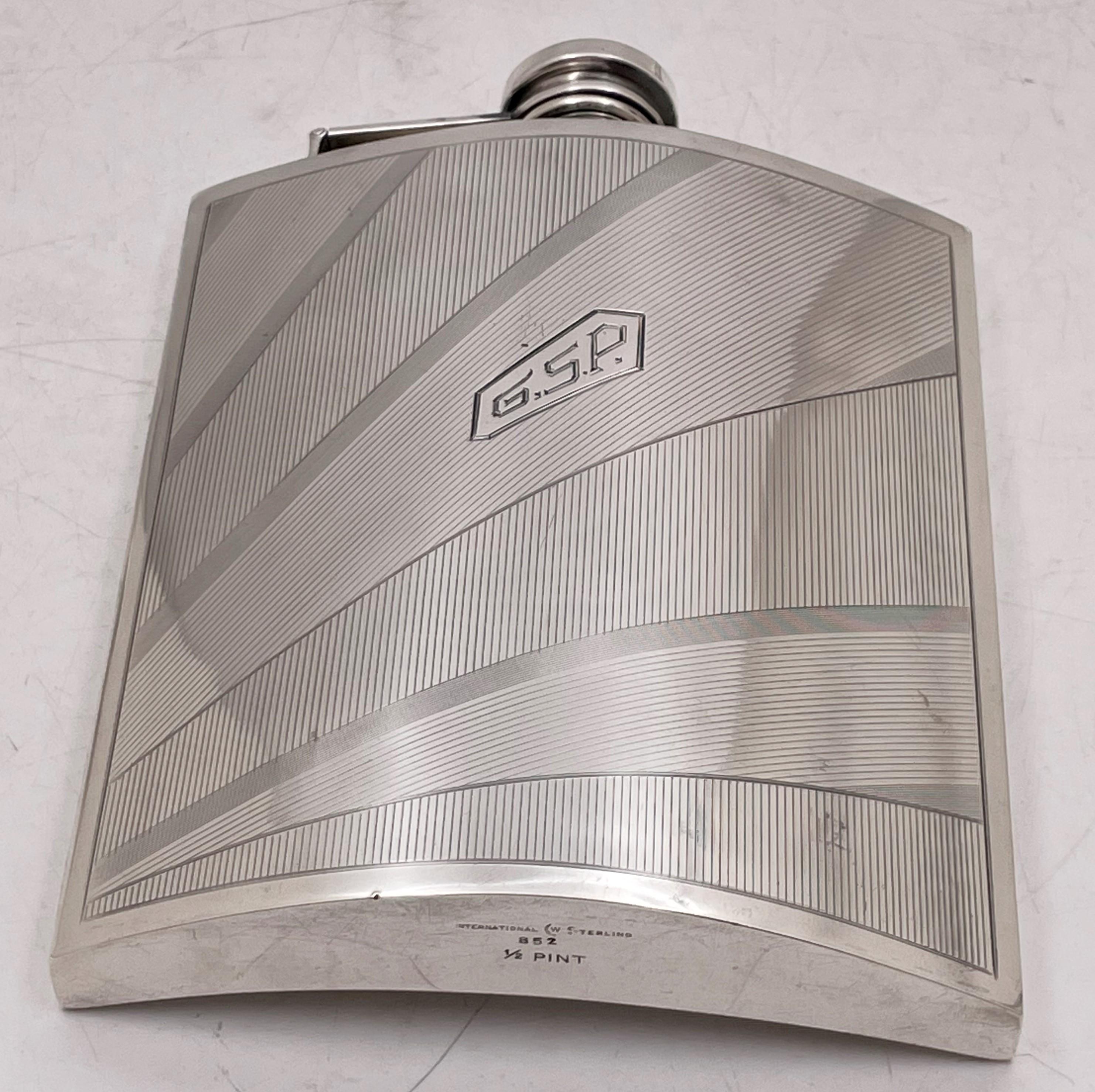 Watrous for International Sterling, sterling silver flask from the early 20th century and in Art Deco style, with an elegant, geometric design. It measures 5 7/8'' in height by 5'' in width by 7/8'' in depth, and bears hallmarks as shown. 

Watrous
