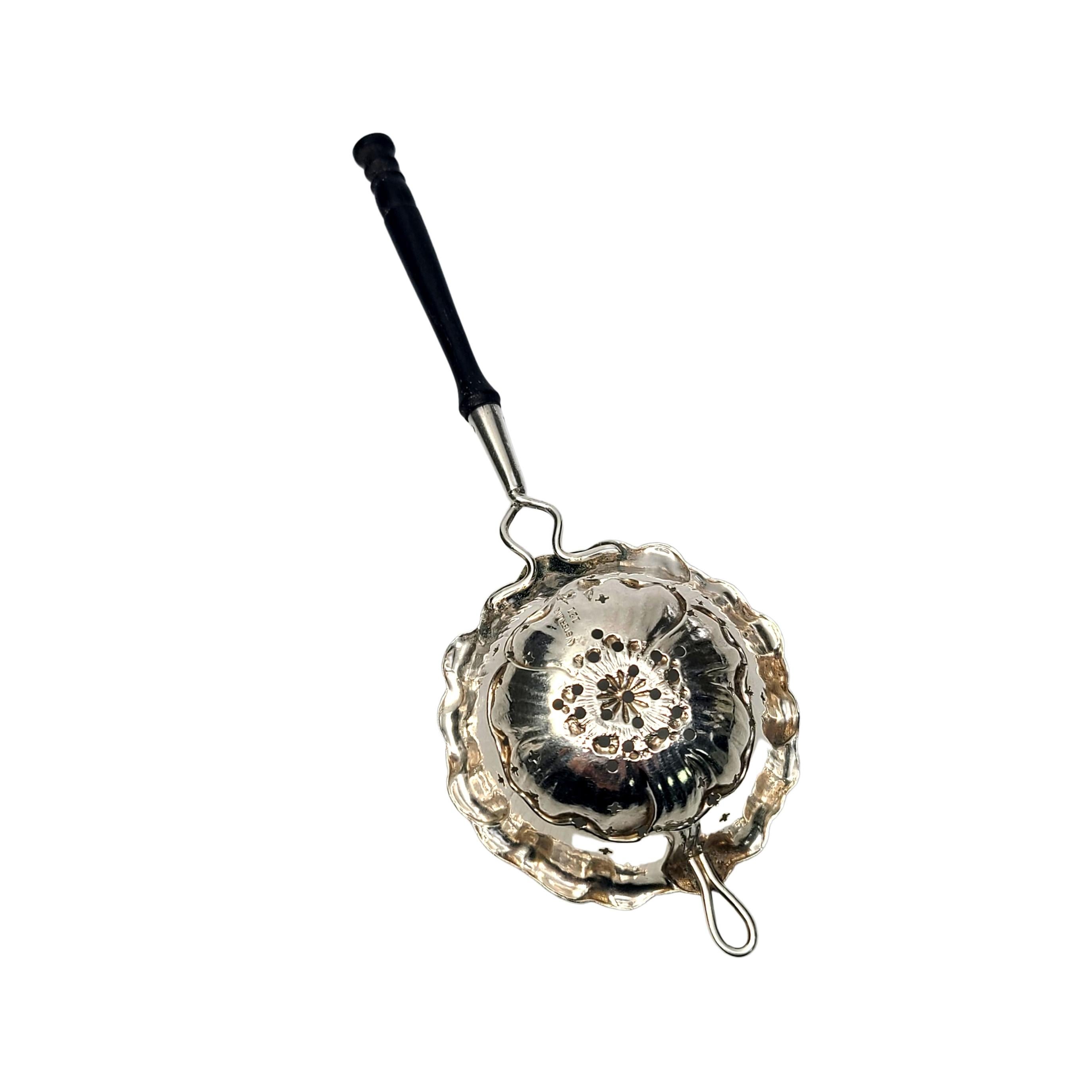Sterling silver tea strainer by Watrous Mfg Co #121.

This tea strainer features a black handle and a pierced star design in a flower shaped bowl with crimped edges.

Measures approx 6 1/2