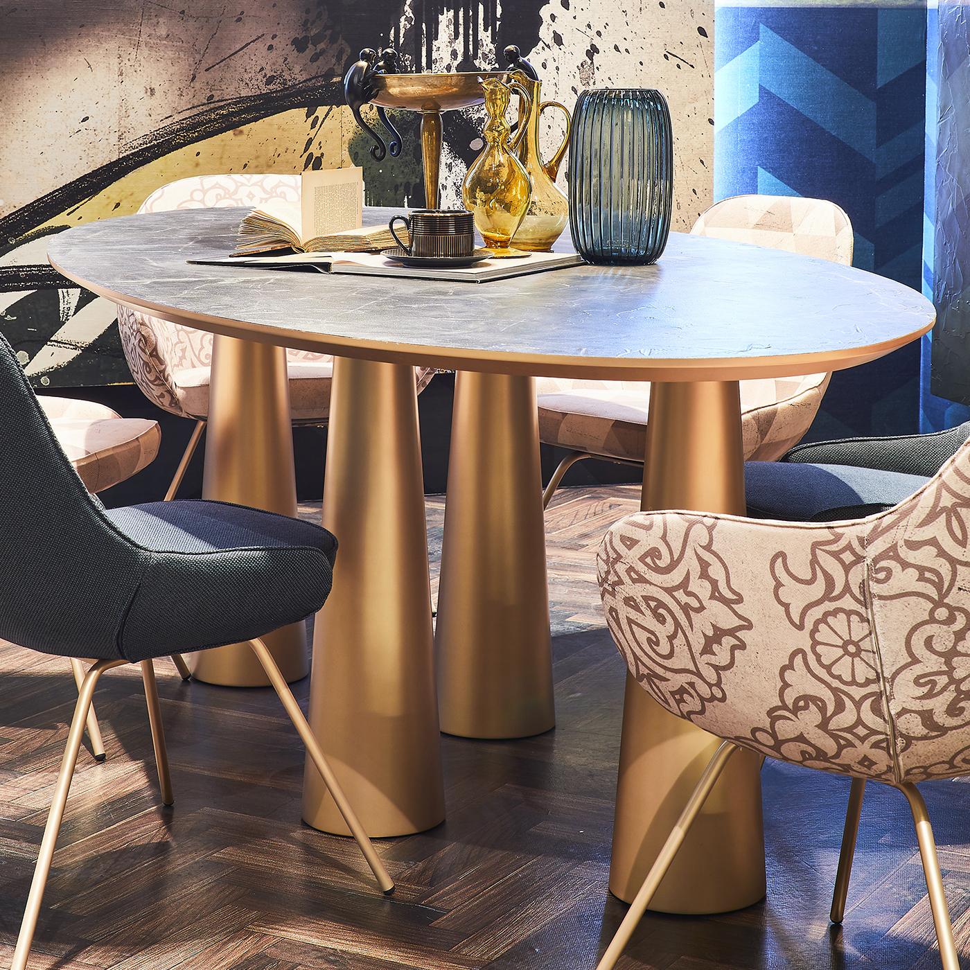 The unique design of this table lends it an unconventional and eclectic allure that will stand out in a modern interior. The oval MDF top is covered by a material surface that is hand applied and finished with a matte, non-toxic resin and features