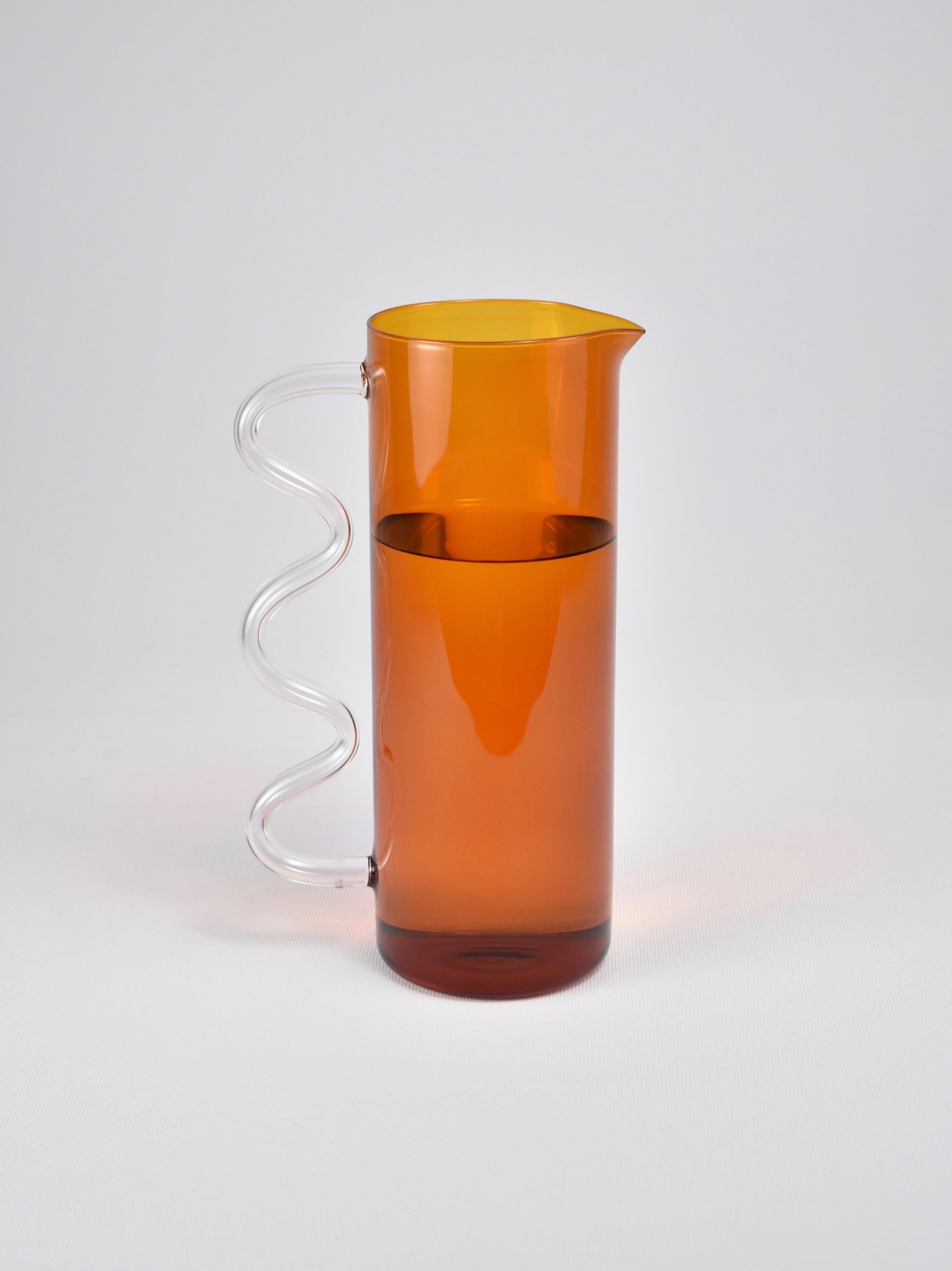 A glass pitcher in amber with a clear wavy handle. May be used for holding flowers, watering plants, a pitcher for juice or any other use you can think of. Designed by Sophie Lou Jacobsen in New York.

Made of lightweight and durable borosilicate