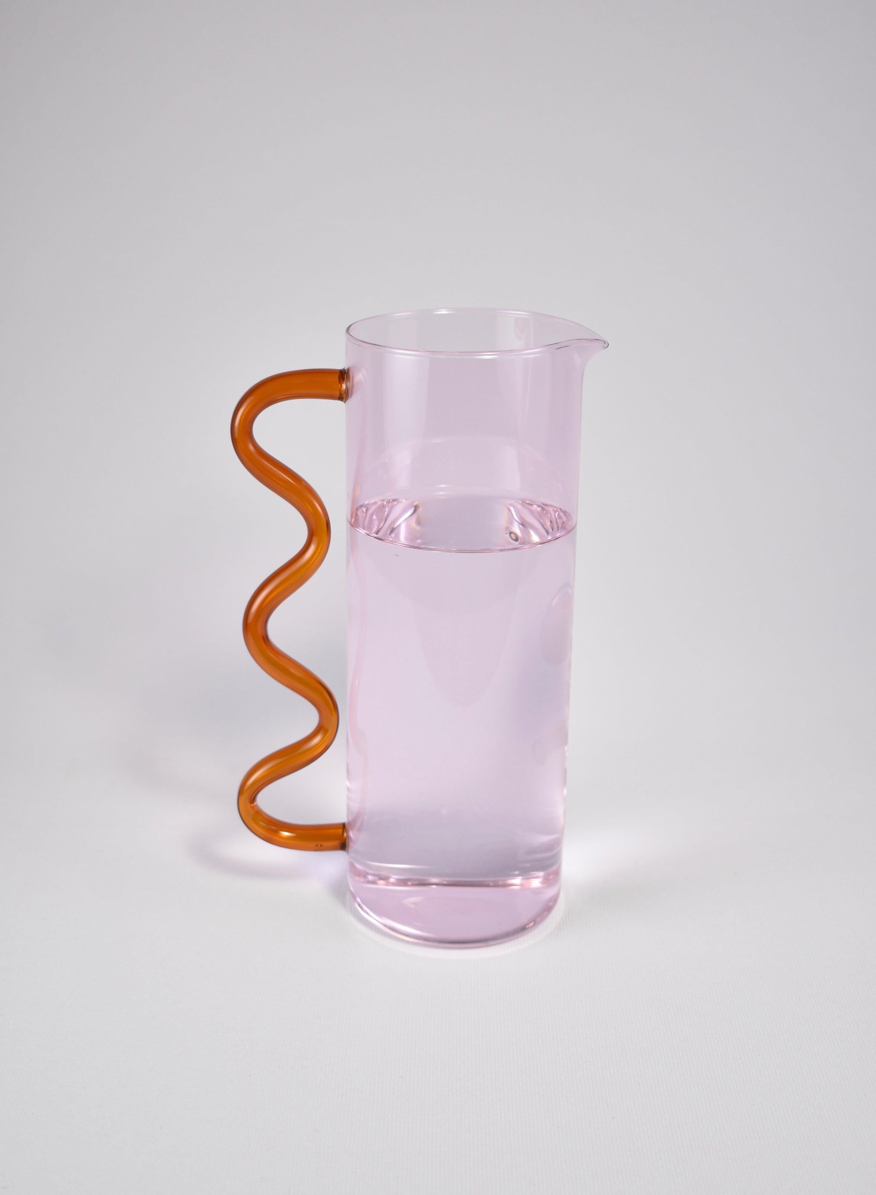 A glass pitcher in pink with an amber wavy handle. May be used for holding flowers, watering plants, a pitcher for juice or any other use you can think of. Designed by Sophie Lou Jacobsen in New York.

Made of lightweight and durable borosilicate
