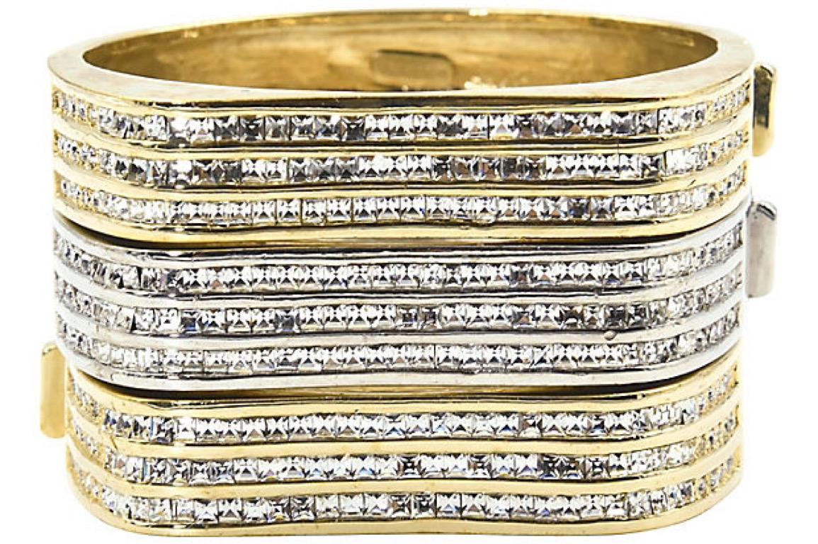 Beautifully made Italian bangle bracelets featuring three rows of crystals across the front of each bracelet. The front section has a wave design. One bracelet looks like white gold and the other two look like yellow gold. They have a push button