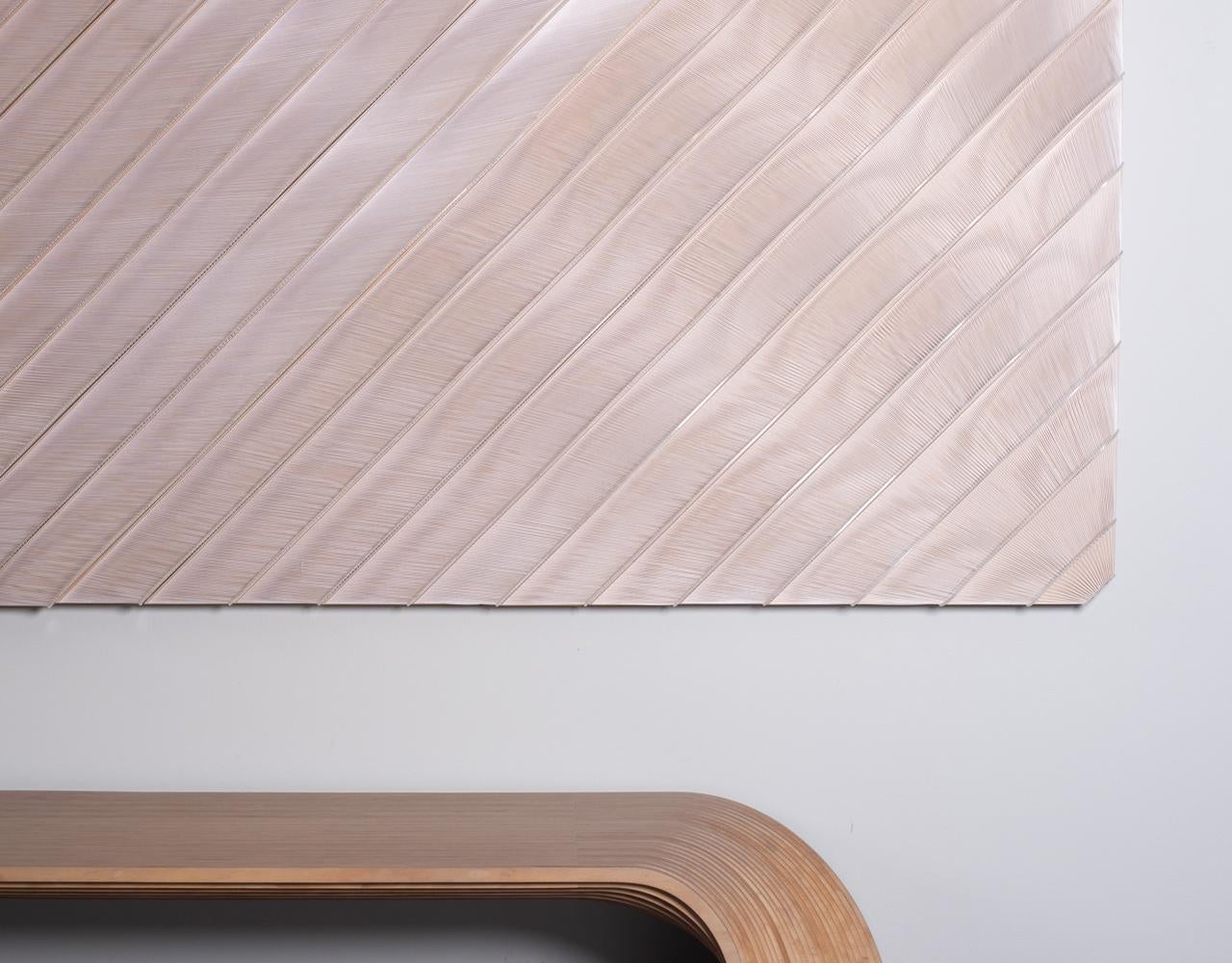 Olas de Hilos es una intrincada escultura mural que explora la convergencia de la precisión material y el movimiento orgánico. Construida con paneles acrílicos cortados con láser y delicadamente enhebrados a mano, la pieza capta la esencia de la