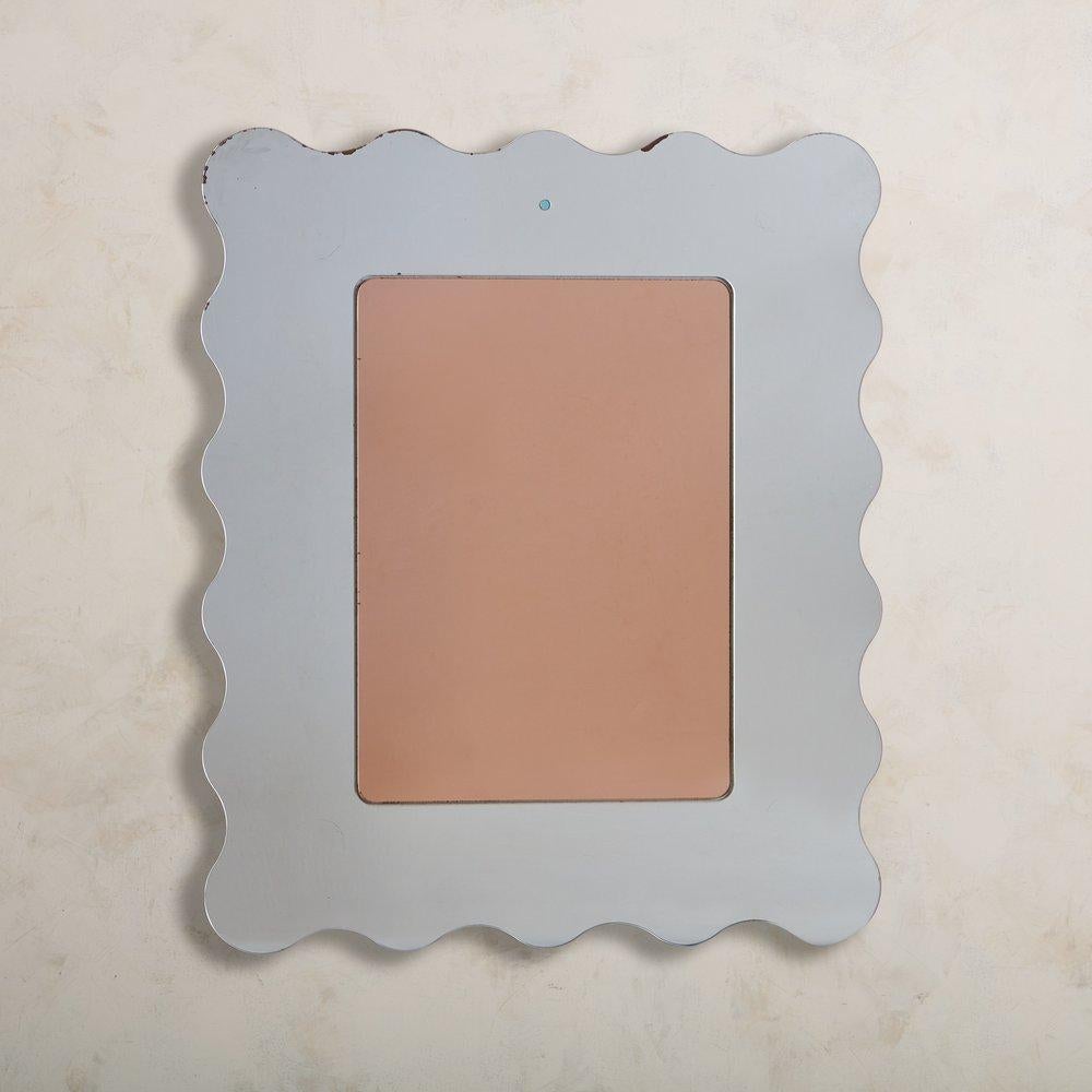 A beautiful Italian rose tinted mirror featuring a thick rectangular mirrored glass frame with a wavy edge. This piece has a wood backing and hardware for hanging. It would look stunning in a powder room or entryway. Sourced in Italy, 1970s.