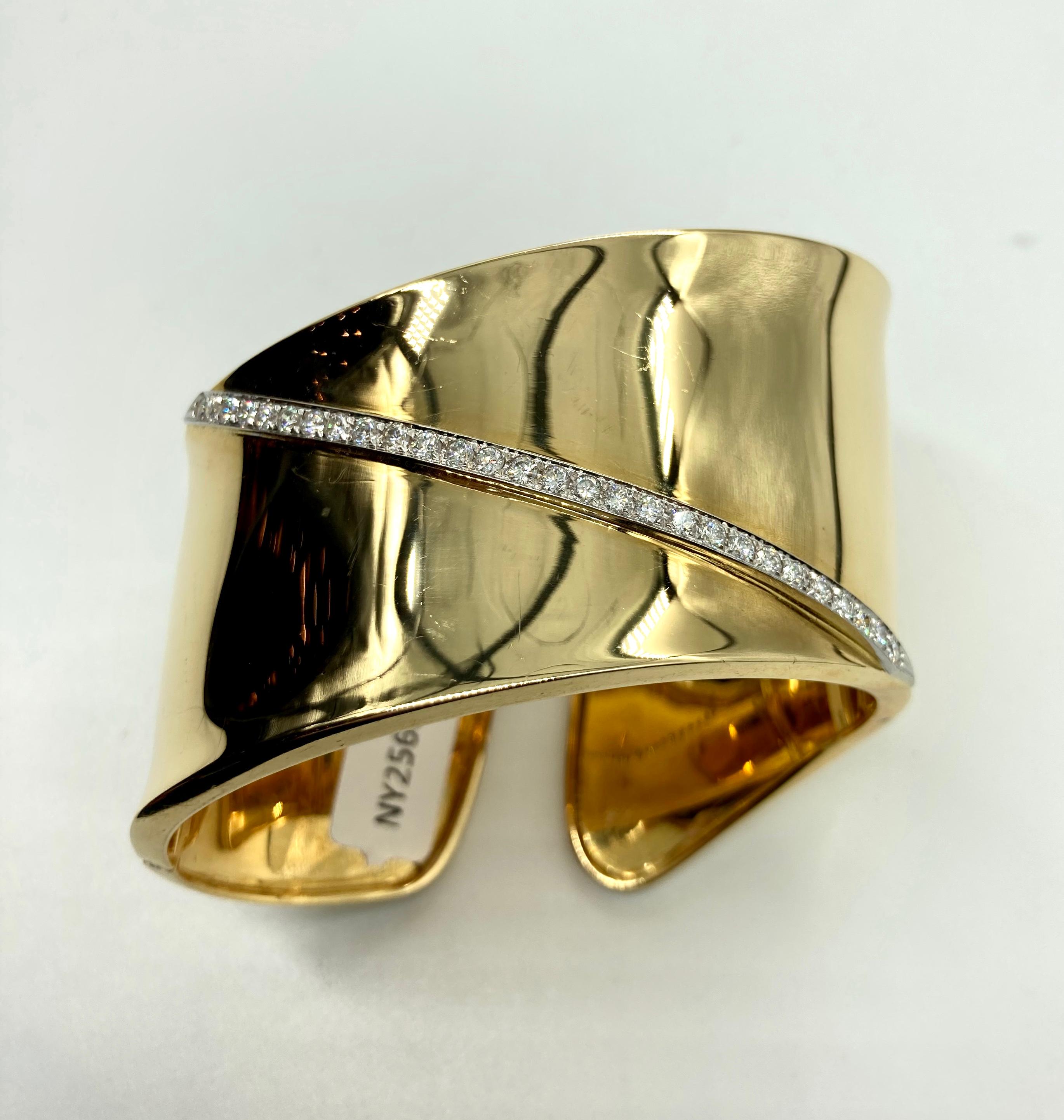 A chic 18 karat yellow gold cuff bracelet of wavy design with 0.85 carats of diamonds. Weighs 75 grams.