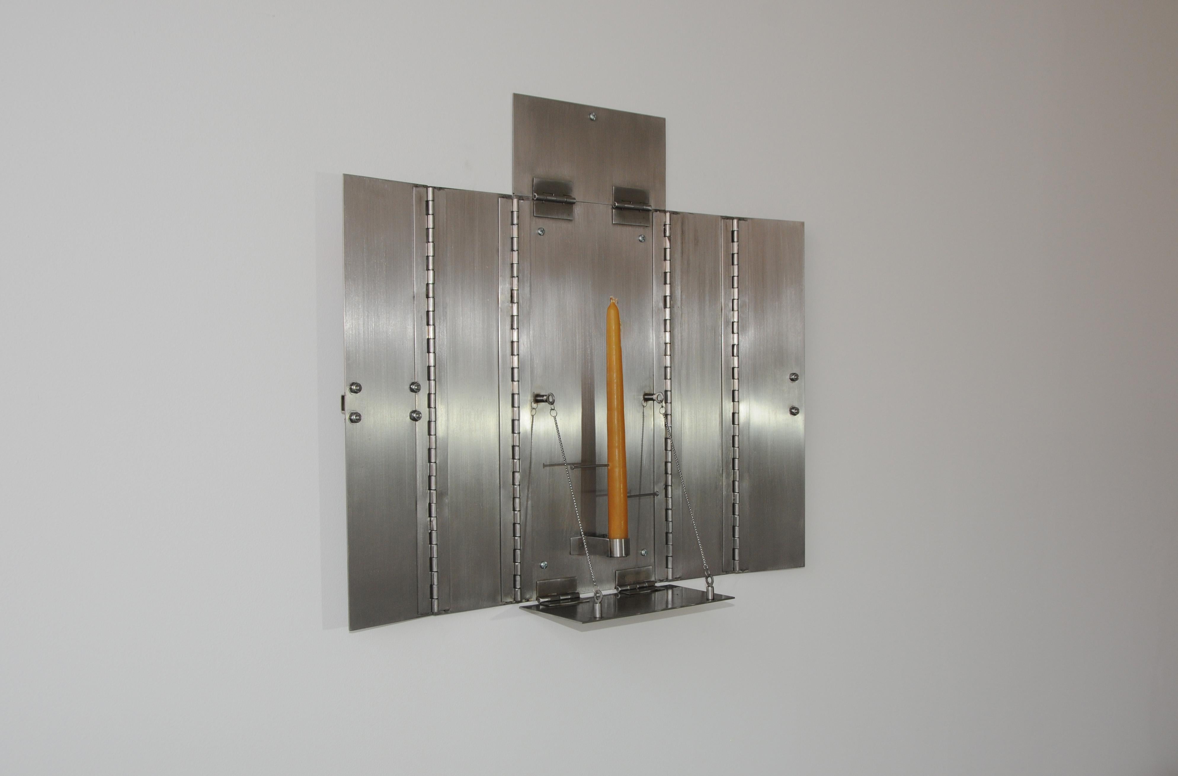 A candle holder rendered in stainless steel is mounted onto the wall as an altar panel painting that folds closed to simulate a medical cabinet. The candle supported by the metal structure is pierced by nails at different heights marking time
