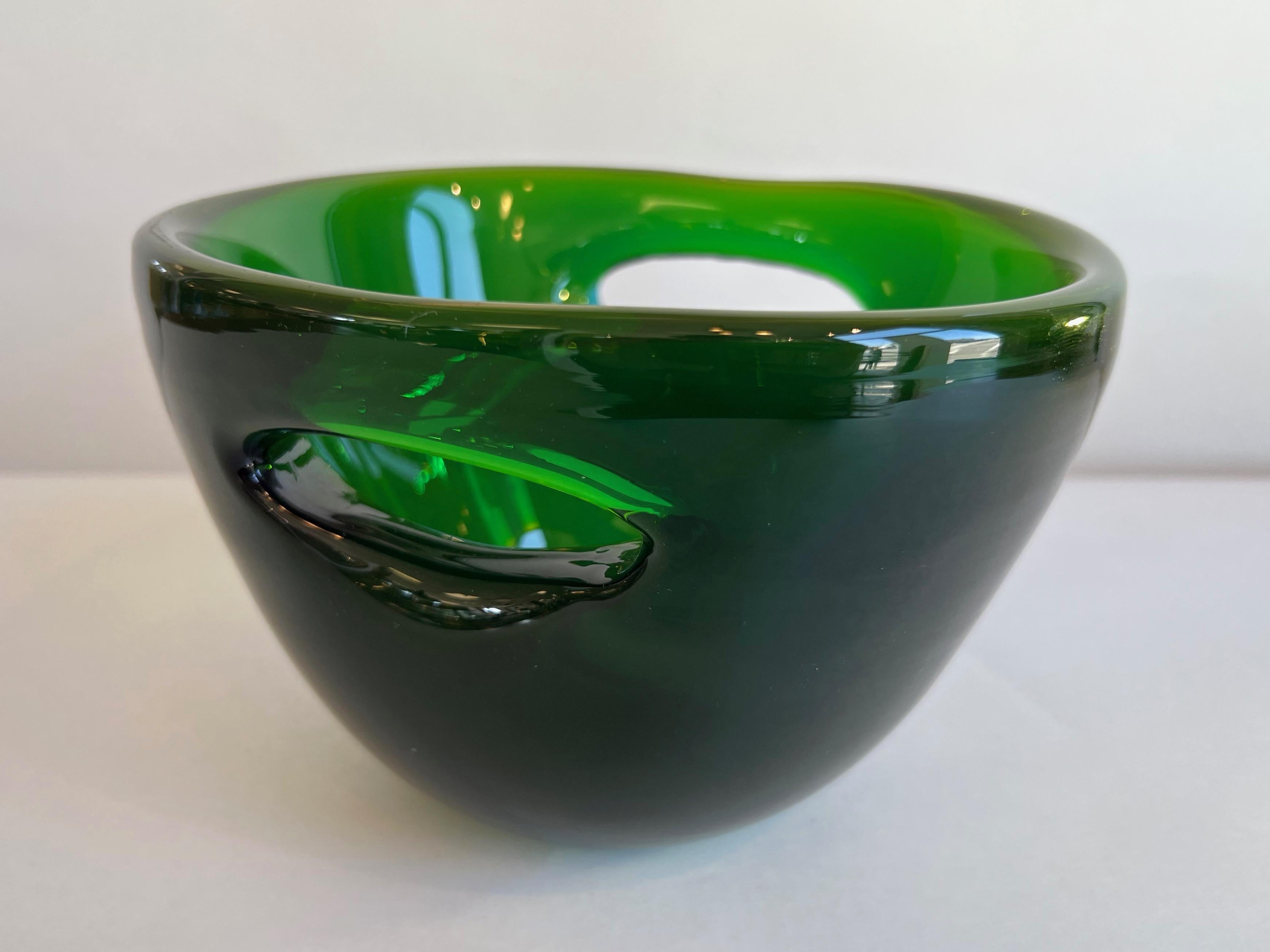 A very rare 1958 Blenko #5819 emerald green double-pierced glass bowl by Wayne Husted.

Produced in this rich and luminous shade of emerald green for only one year—1958—it features a pair of large piercings on either side of its thick-walled body.