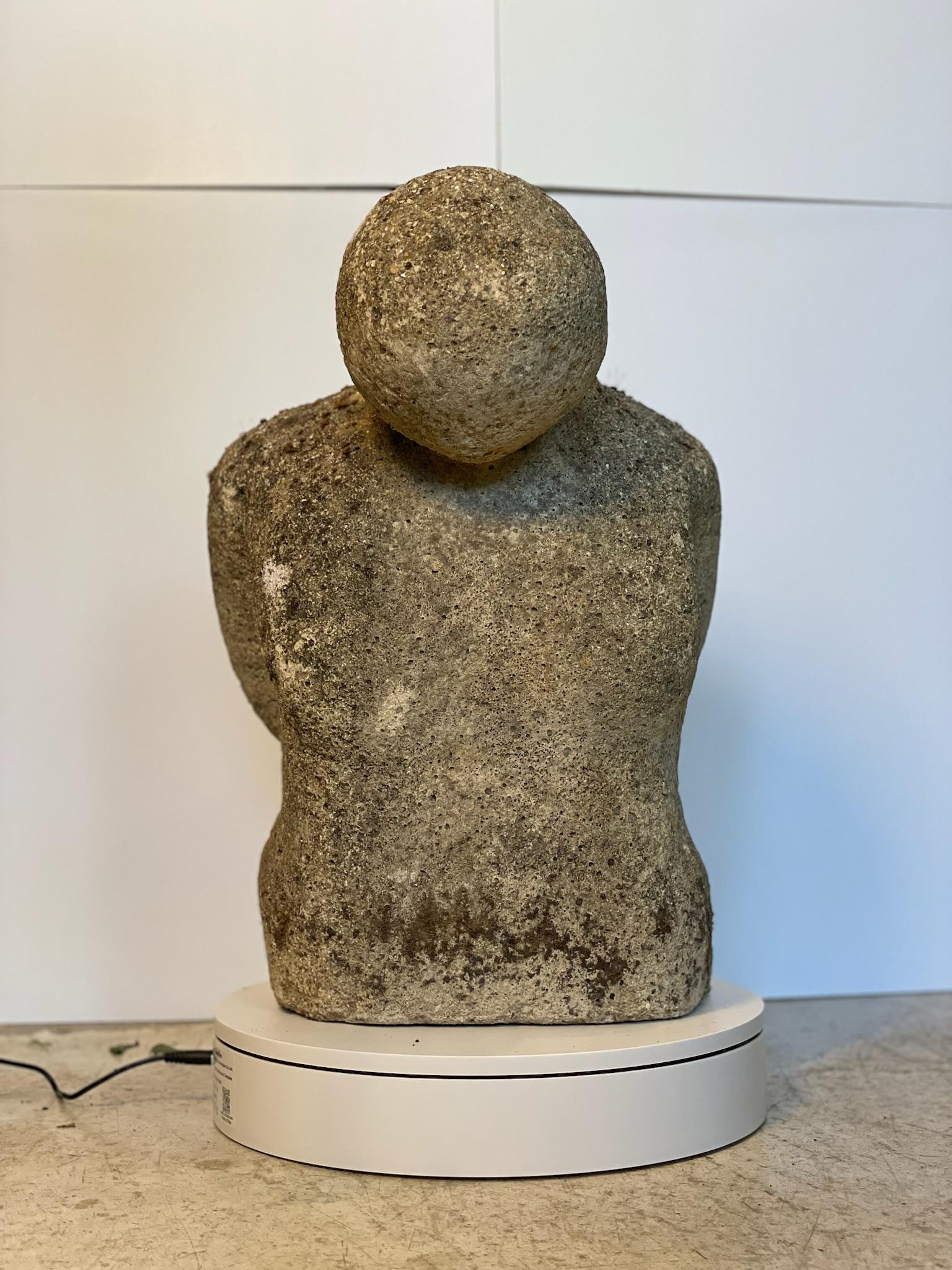 Questa affascinante scultura di torso in pietra presenta un'interpretazione cruda e senza tempo della forma umana, fondendo elementi di arte primitiva e astrazione modernista. Abilmente modellata da quella che sembra essere pietra ricostituita o