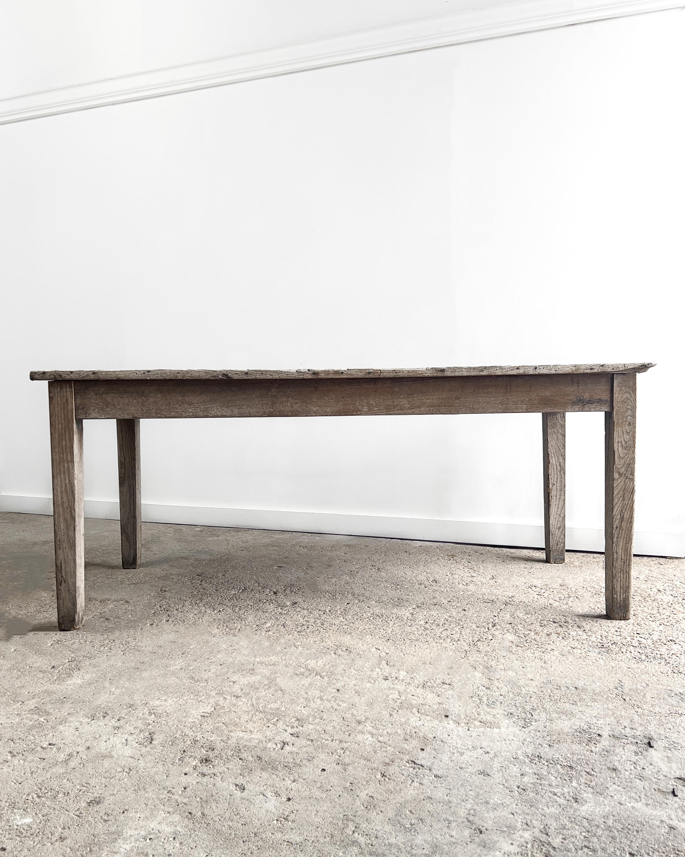 Weathered chestnut farm table from France featuring straightforward lines and gently tapered legs. A drawer in the apron at one end is adorned with a lovely hand-turned wooden knob. The beautifully aged, weathered, knotty, four-board top makes this