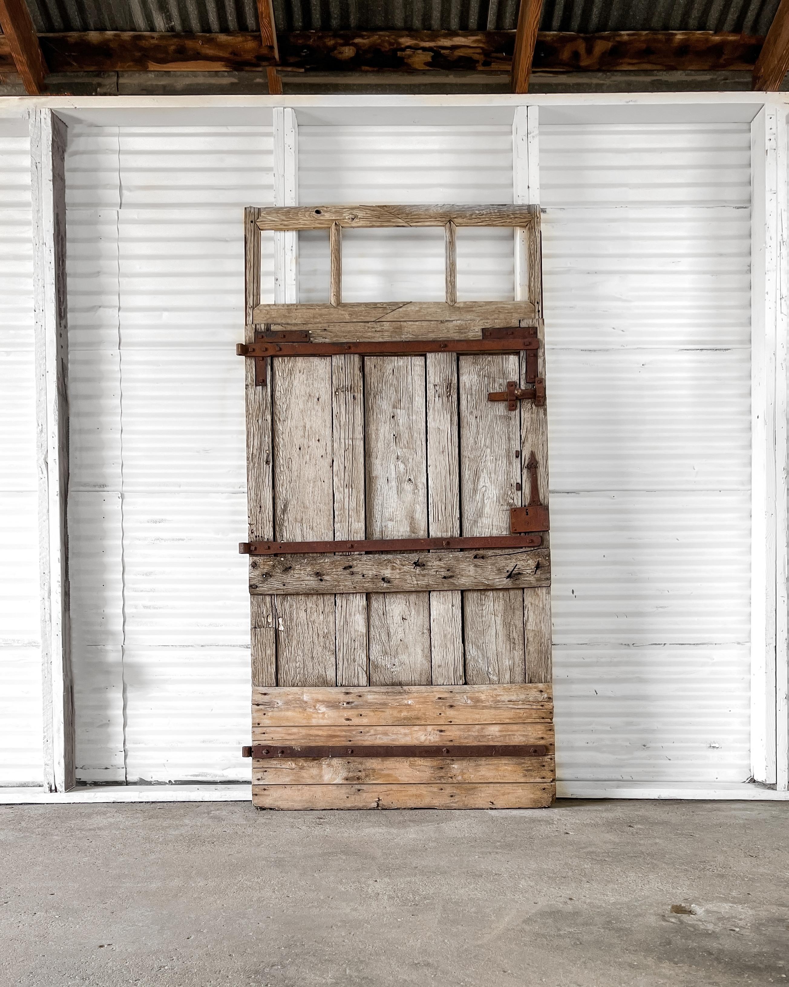 Weathered barn stall door salvaged from a French country farm. Primitive in design, the door is fitted with hand-forged iron hardware. Use to separate two spaces as a barn slide to bring a sense of history and texture to your home’s decor.

Salvaged