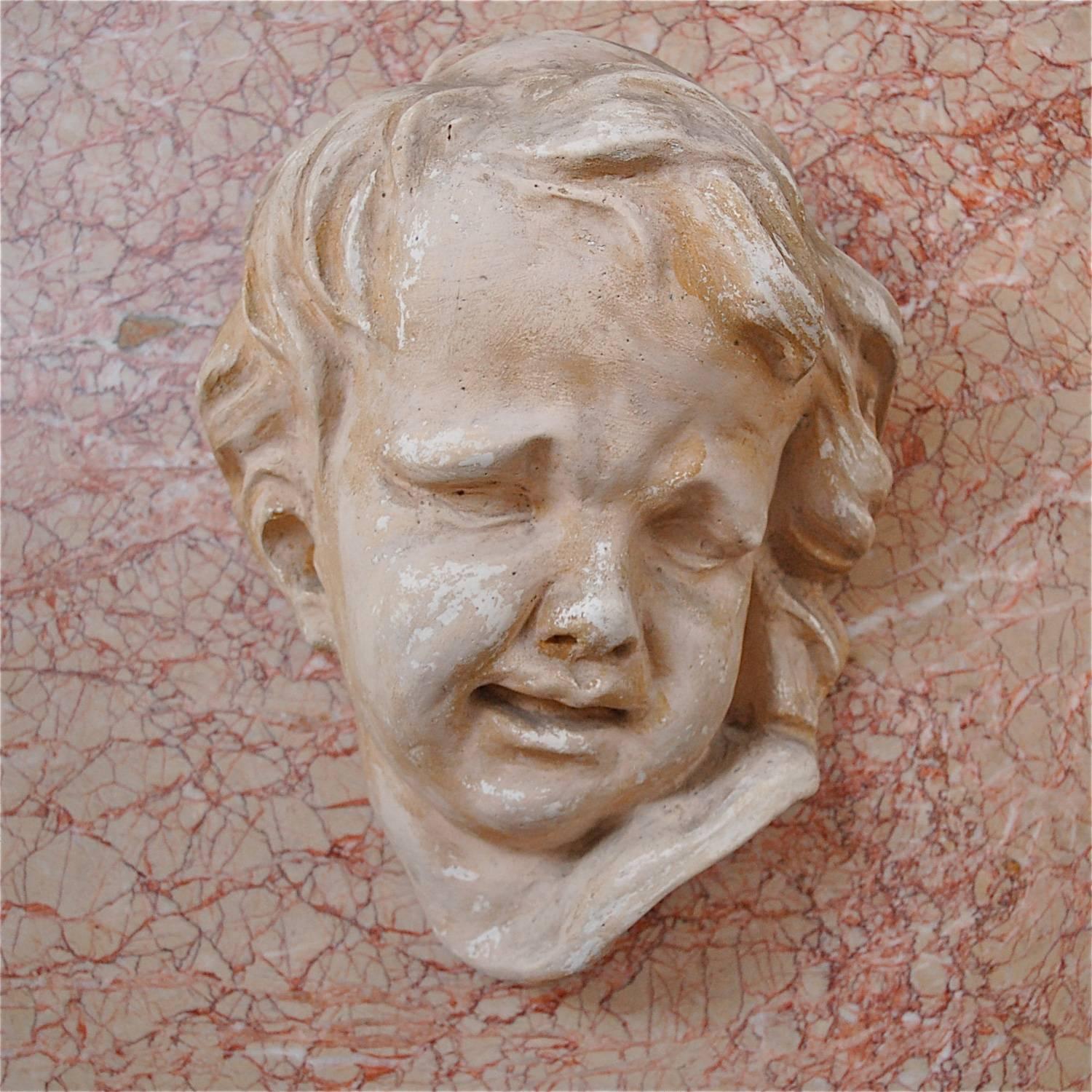 You cannot help but be drawn in by the dramatic expression of this cherub, angel or child's face. The natural ageing of the sculpture that's occurred over the years has added character and tone. This piece is cast in plaster by an unknown artist,