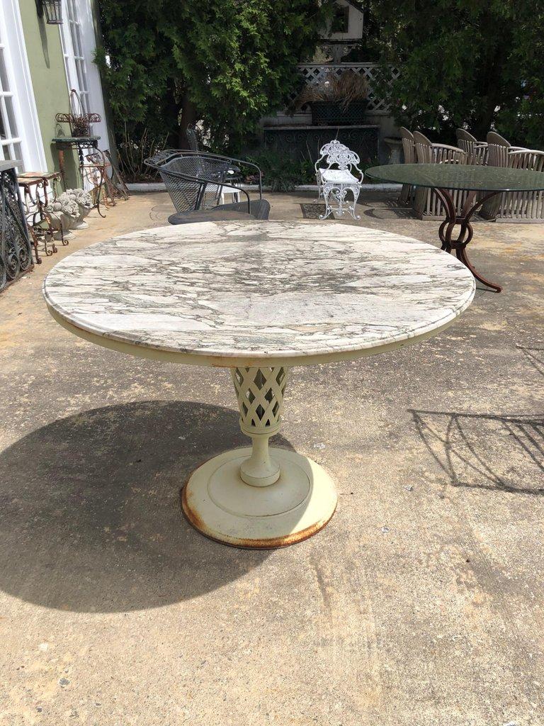 Weathered Carrara marble-topped vintage iron patio table. The marble top is weathered from being outside. Base has some rust but can be painted any color for an additional fee. No chairs are included with this table. Just marble top and iron base.