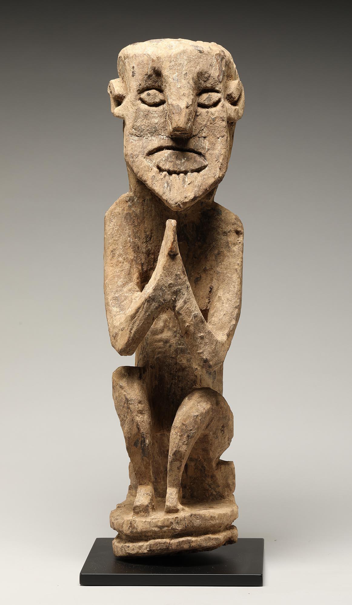 Old weathered tribal squatting spring figure with hands raised in namaste position, traces of clay and incrustation, expressive carved open mouth and eyes. These were protective figures used in Nepal. Late 19th to early 20th century, 17 inches high.