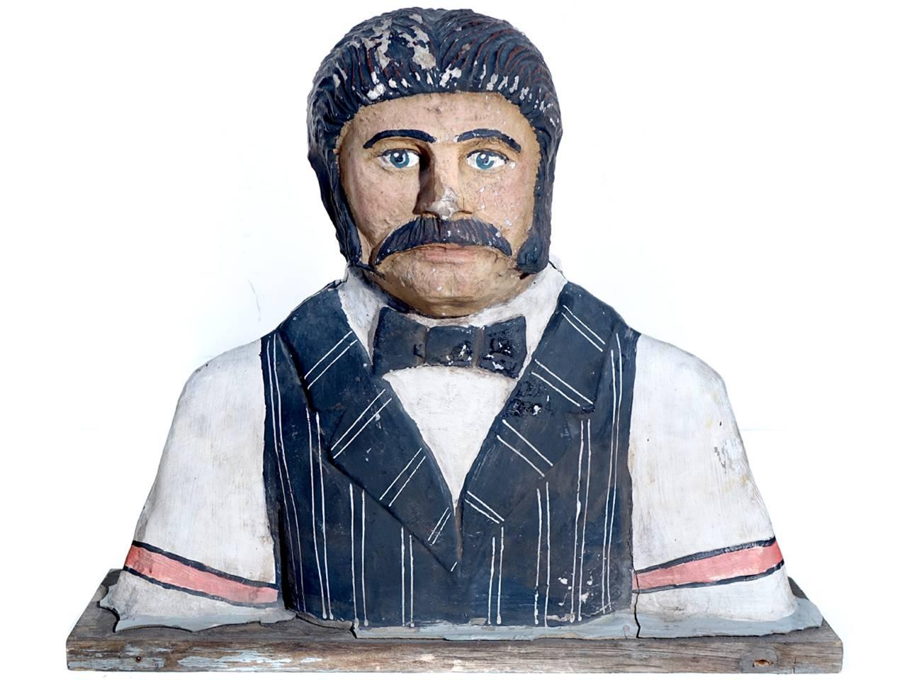 This life-sized character of a period bar tender was mounted outside on top of the saloons main sign. It's two sided with heads facing both ways. It's spent many years outside and has nice age with a weathered patina. A great piece of Folk Art.