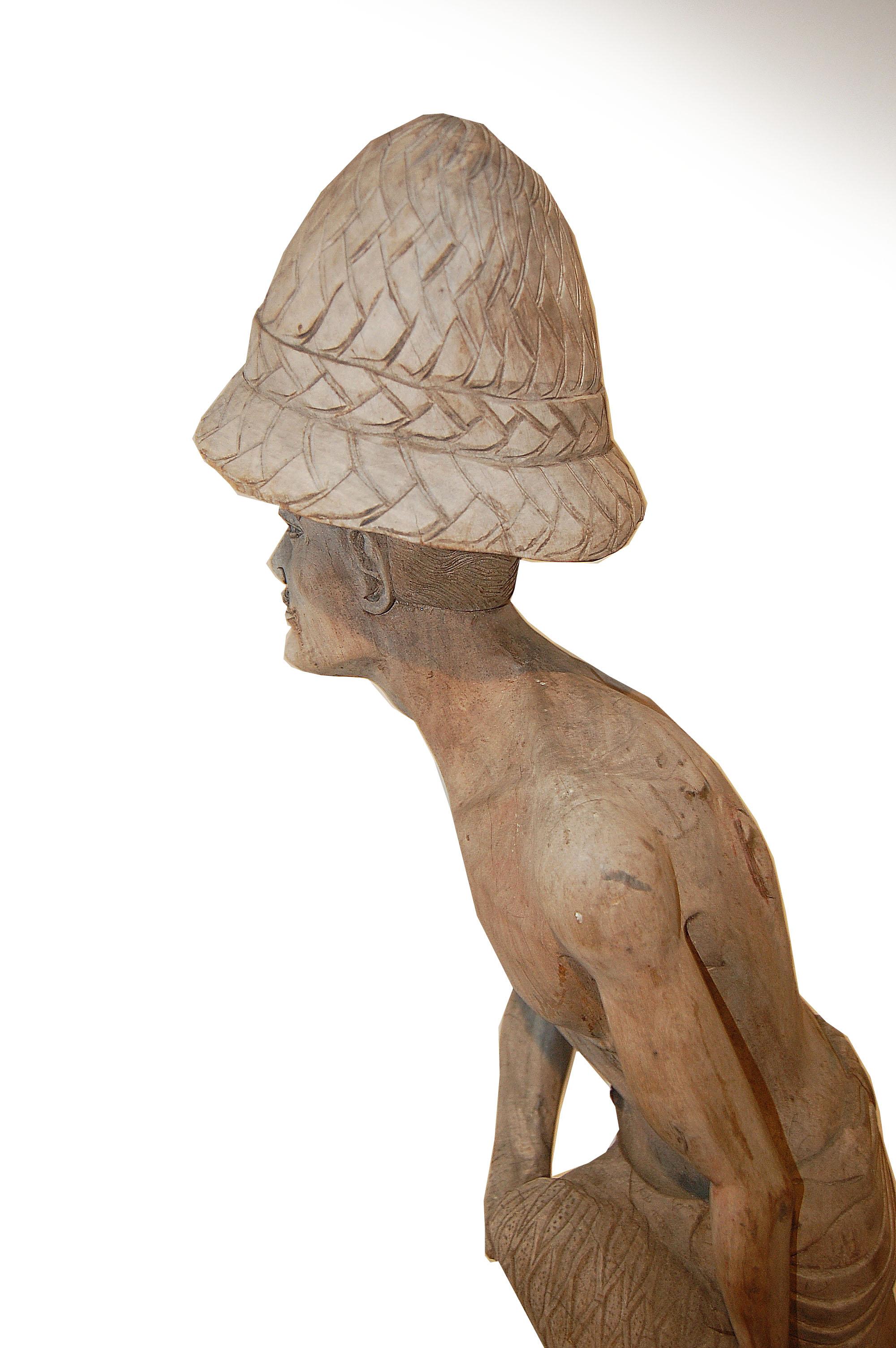 Ogni tanto ci imbattiamo in figure come questa scultura, che raffigura un uomo che tiene in mano una rete da pesca, e che semplicemente attirano la nostra attenzione. La scultura mostra segni di cedimento del legno alle intemperie sul viso, sul