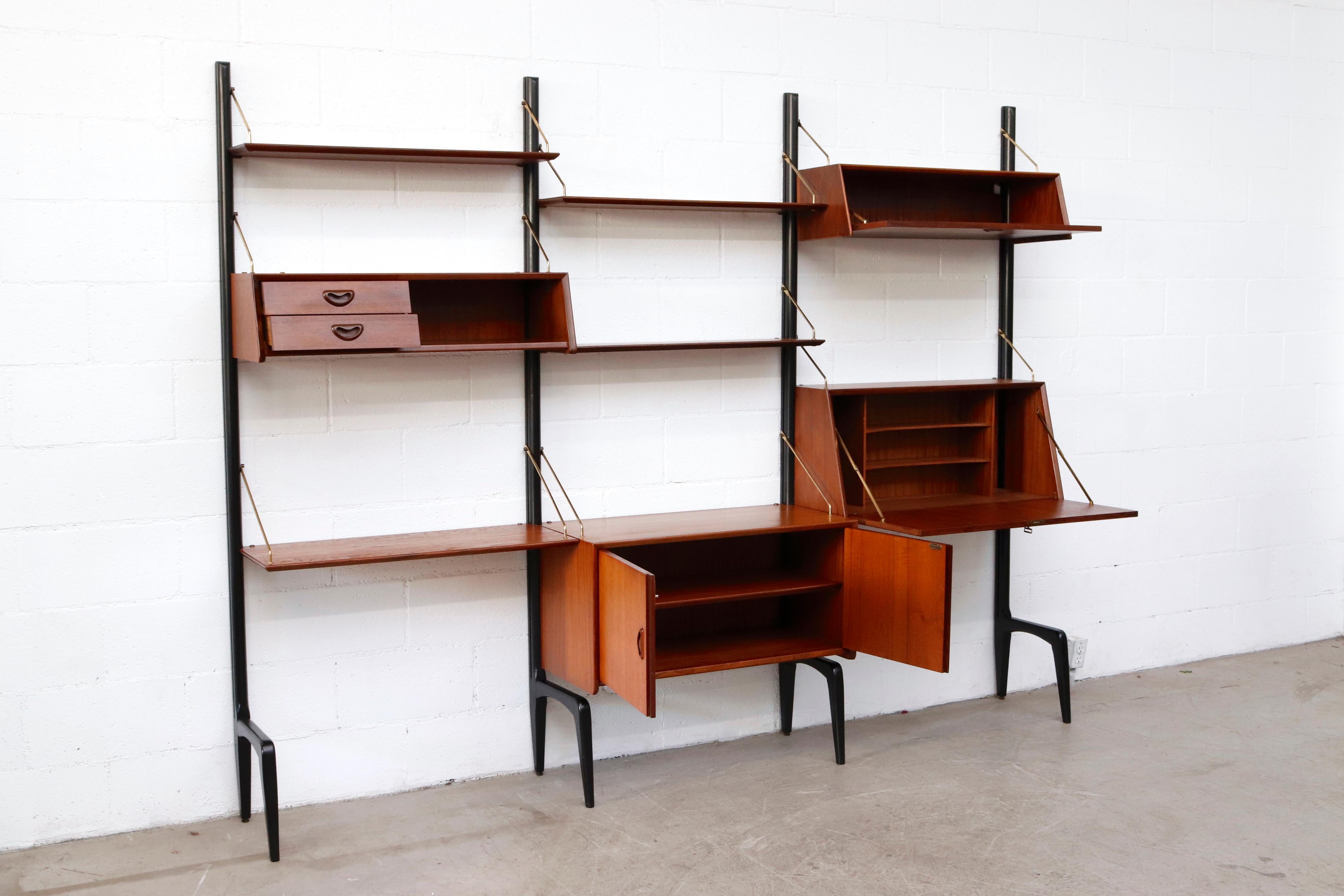 Handsome Louis Van Teeffelen 3 section standing wall unit for WeBe. Lightly refinished teak shelving and storage cabinets with drop down desk. in good overall condition with visible patina including a small burn mark on one cabinet, and brass
