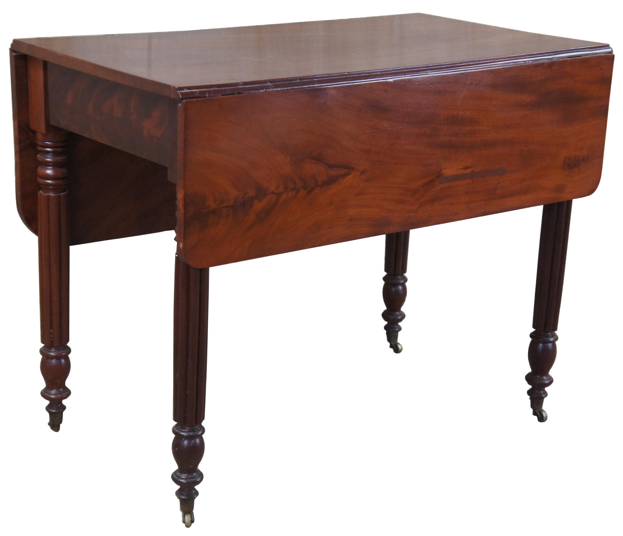 American Empire style table by Weber Furniture of Chicago, Illinois. Handmade from flame mahogany. Features a unique drop leaf with two different sized leaves, reeded legs and arrow feet over petite casters.
   