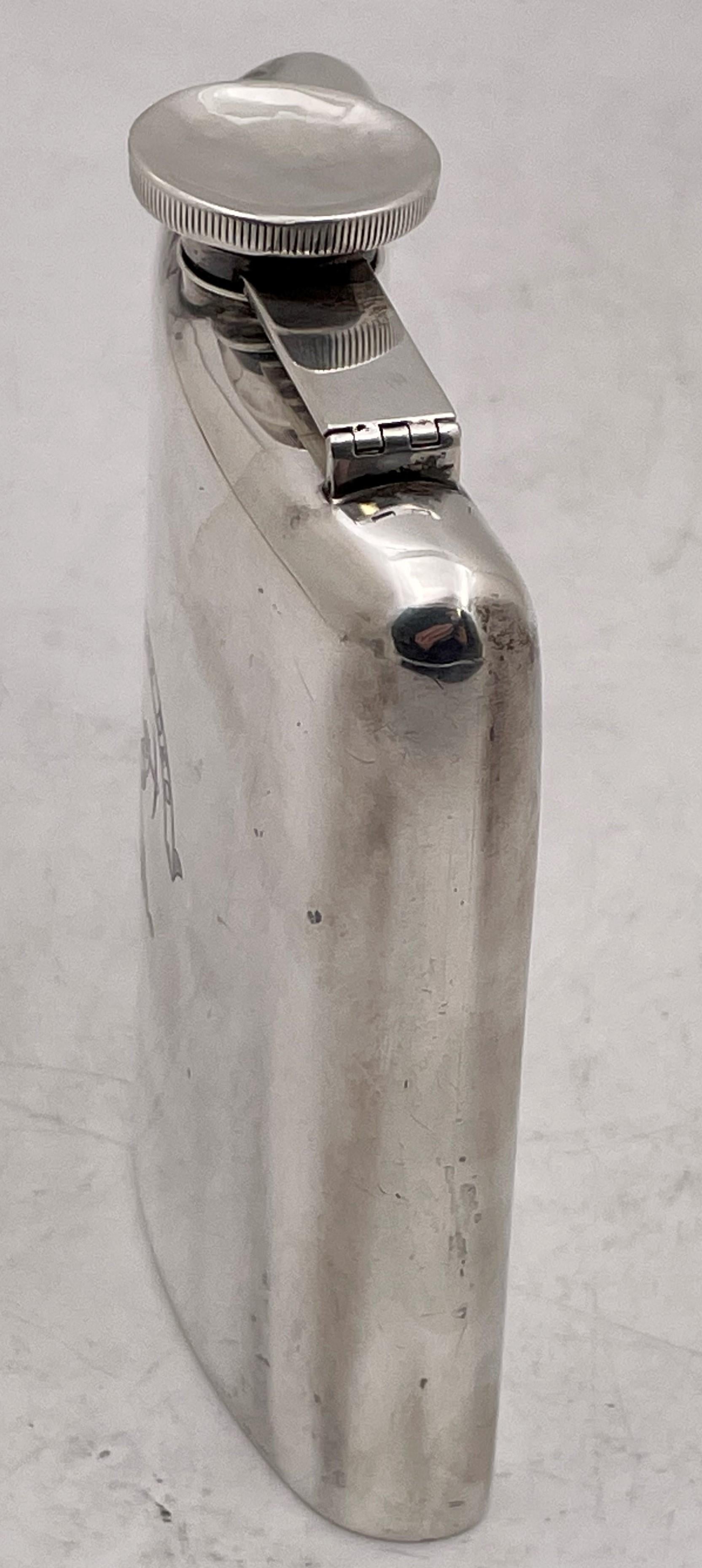 Webster sterling silver hip flask from the early 20th century, with an engraved design at the center, having a screw top, measuring 5 1/8'' in length by 4 3/8'' in width by 1 1/4'' in height, containing half a pint, and bearing hallmarks as shown.