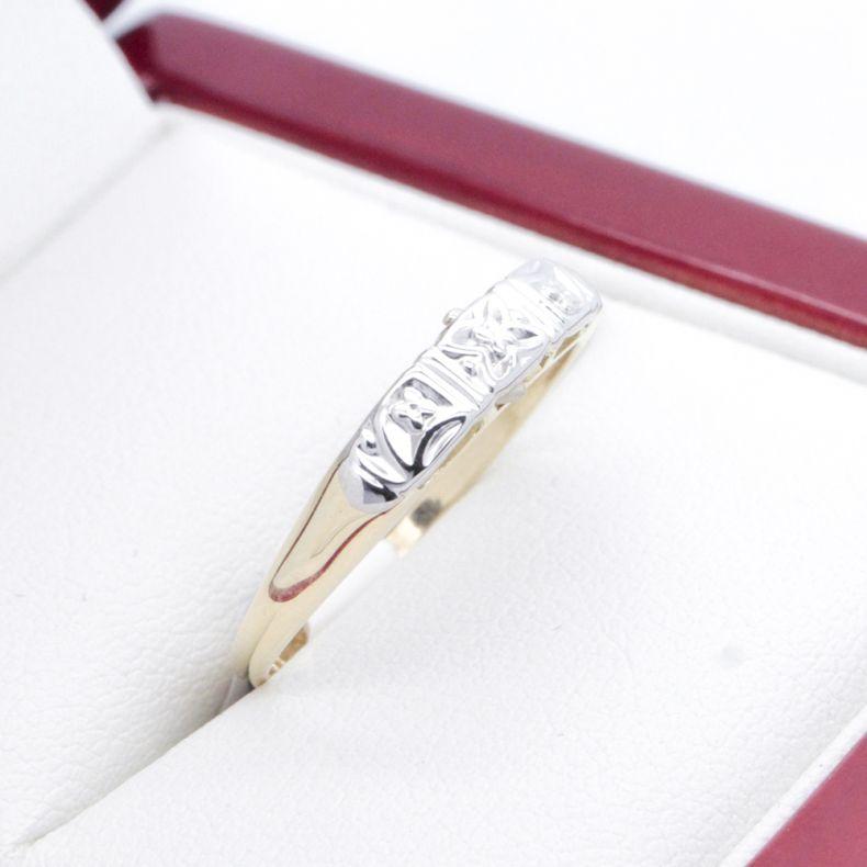 Simple, elegant two tone wedding band with a yellow gold shank and white gold engraved front.  Would go well with any engagement ring from the 1920-1940s era. 
The engraved, shaped front is designed to give the illusion of it being set with