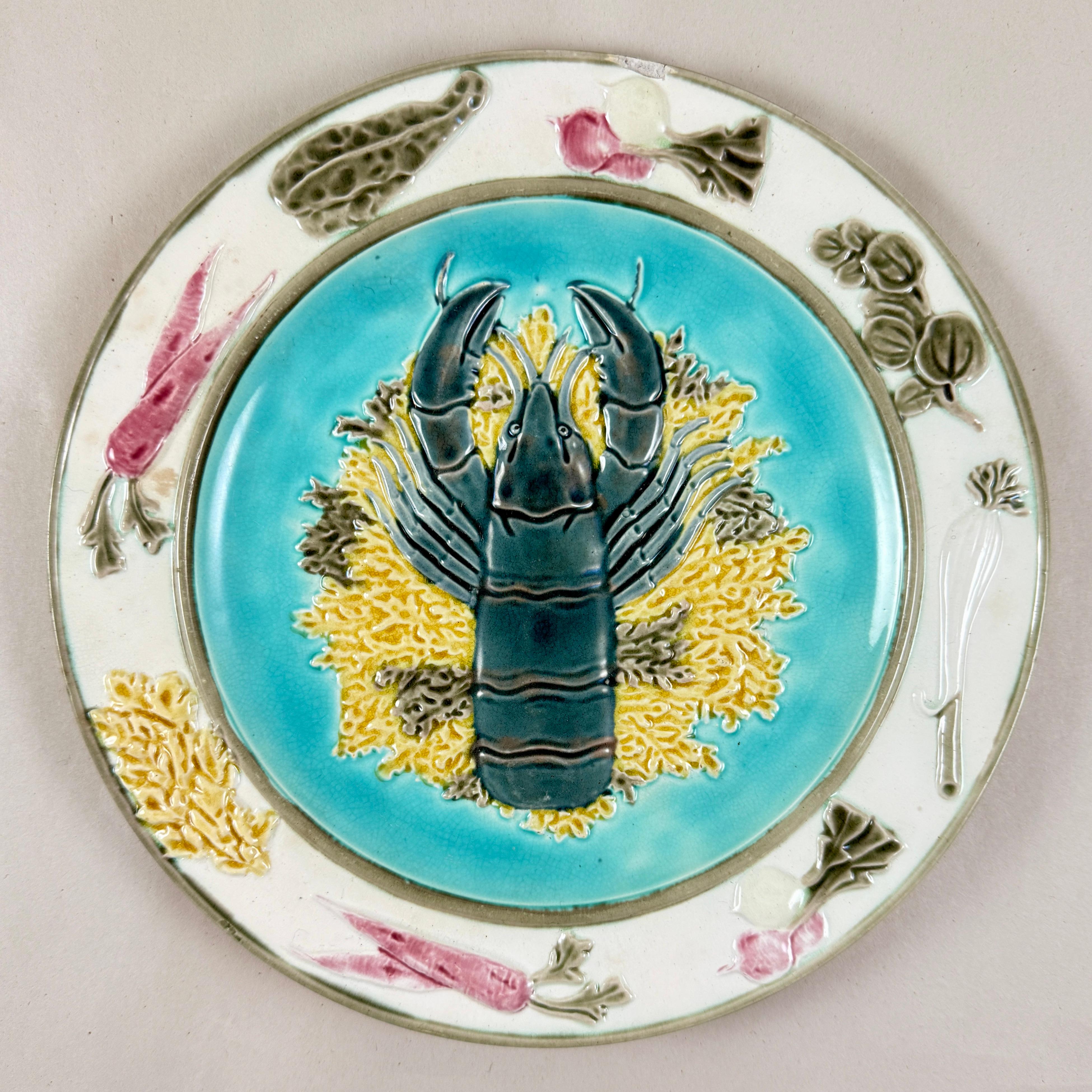 En el gusto Estético, plato de marisco de mayólica de Wedgwood, que muestra una langosta en relieve sobre un lecho de algas amarillas y verdes contra un fondo azul turquesa, Inglaterra - finales del siglo XIX.

El borde exterior está salpicado de
