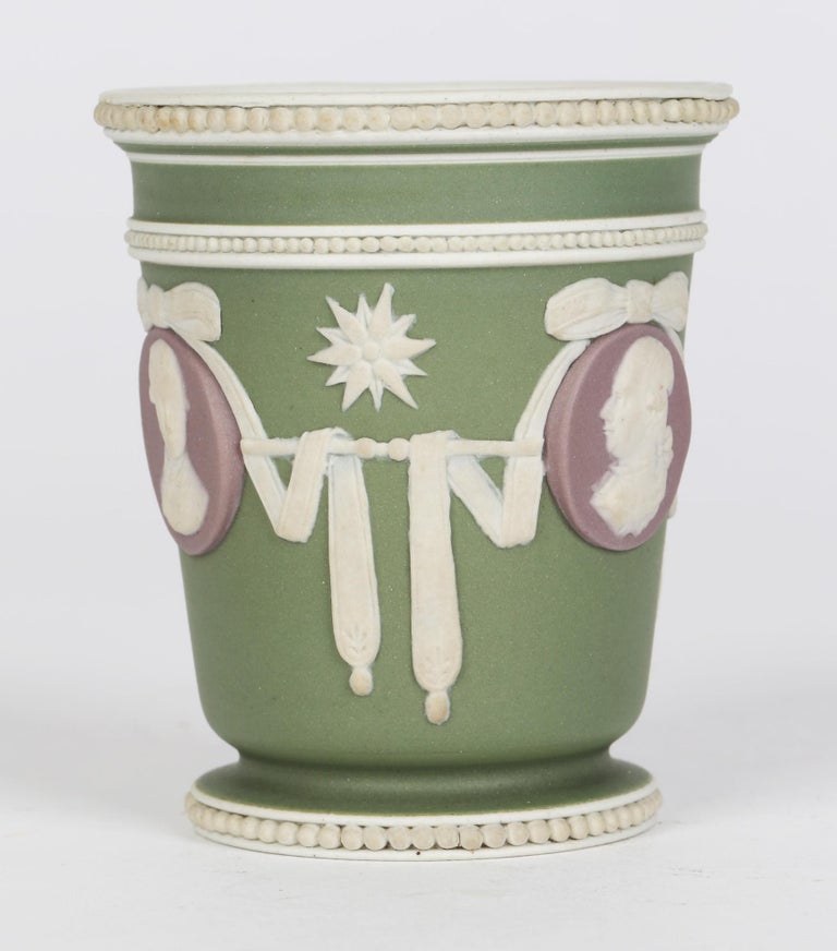 A rare Wedgwood three color jasperware beaker shaped vase applied with portrait medallions dating from circa 1790. The vase stands on a rounded foot with inset beaded rim with a beaker shaped body applied with trailing and bow tied ribbons with star