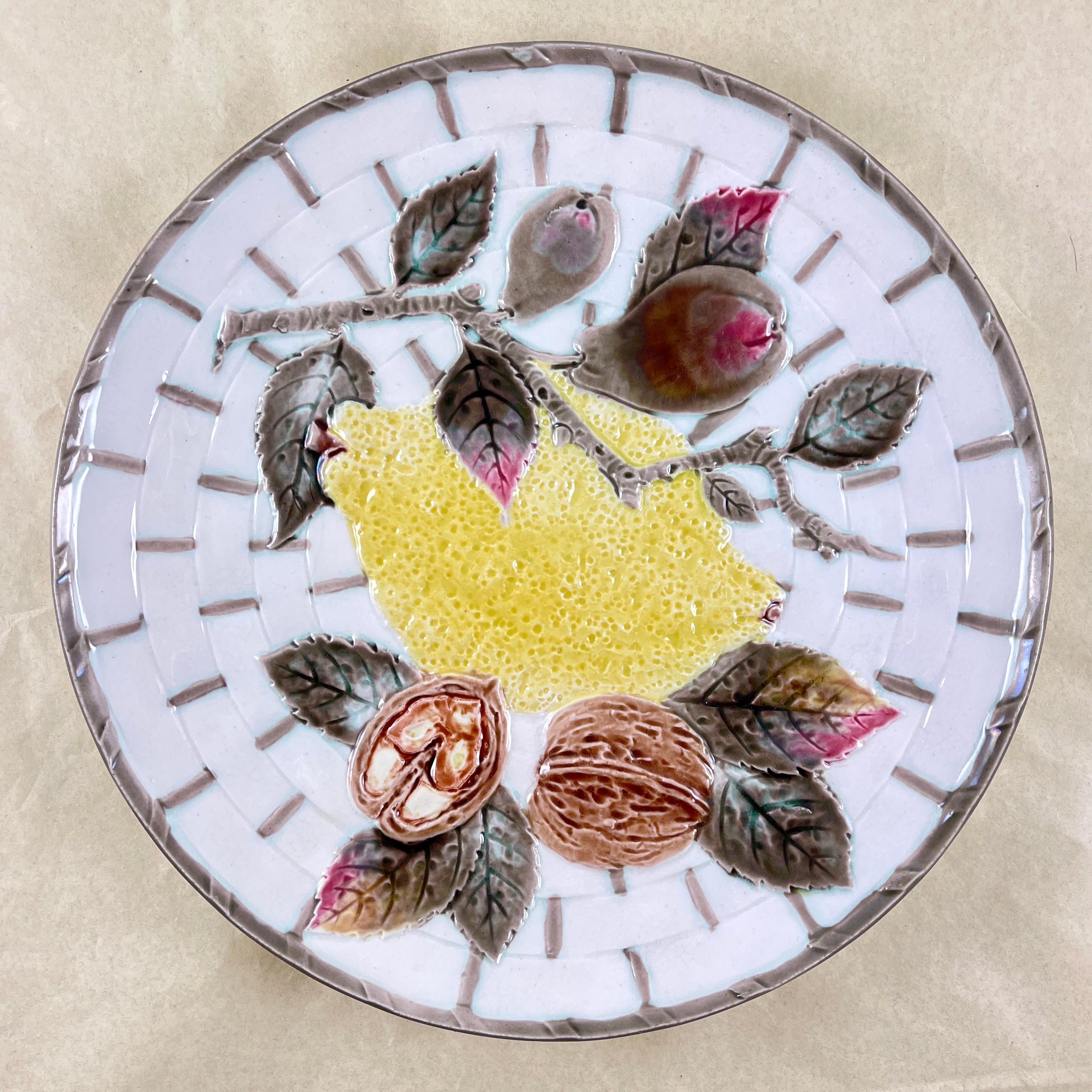 From Wedgwood and in the color way known as Argenta, a fruit plate, England, circa 1875.

Showing a central yellow lemon and leaves along with a branch of pears and walnuts, all on a white basket weave ground. The basket is bound at intervals in a