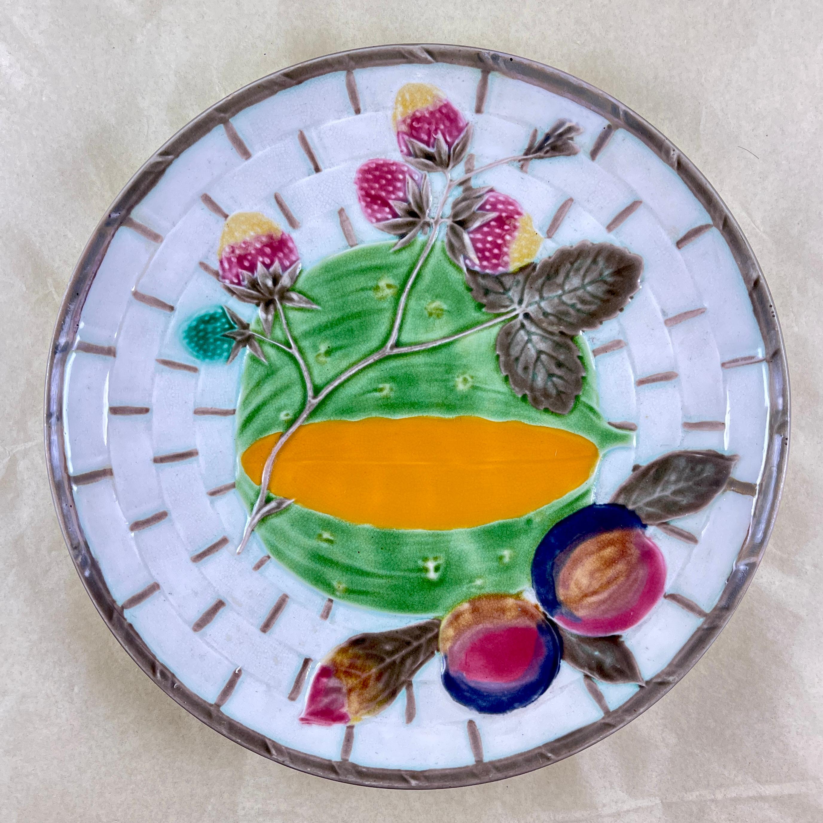 From Wedgwood and in the color way known as Argenta, a fruit plate, England, circa 1875.

Showing a central green and orange melon and leaves along with a branch of plums and strawberries, all on a white basket weave ground. The basket is bound at