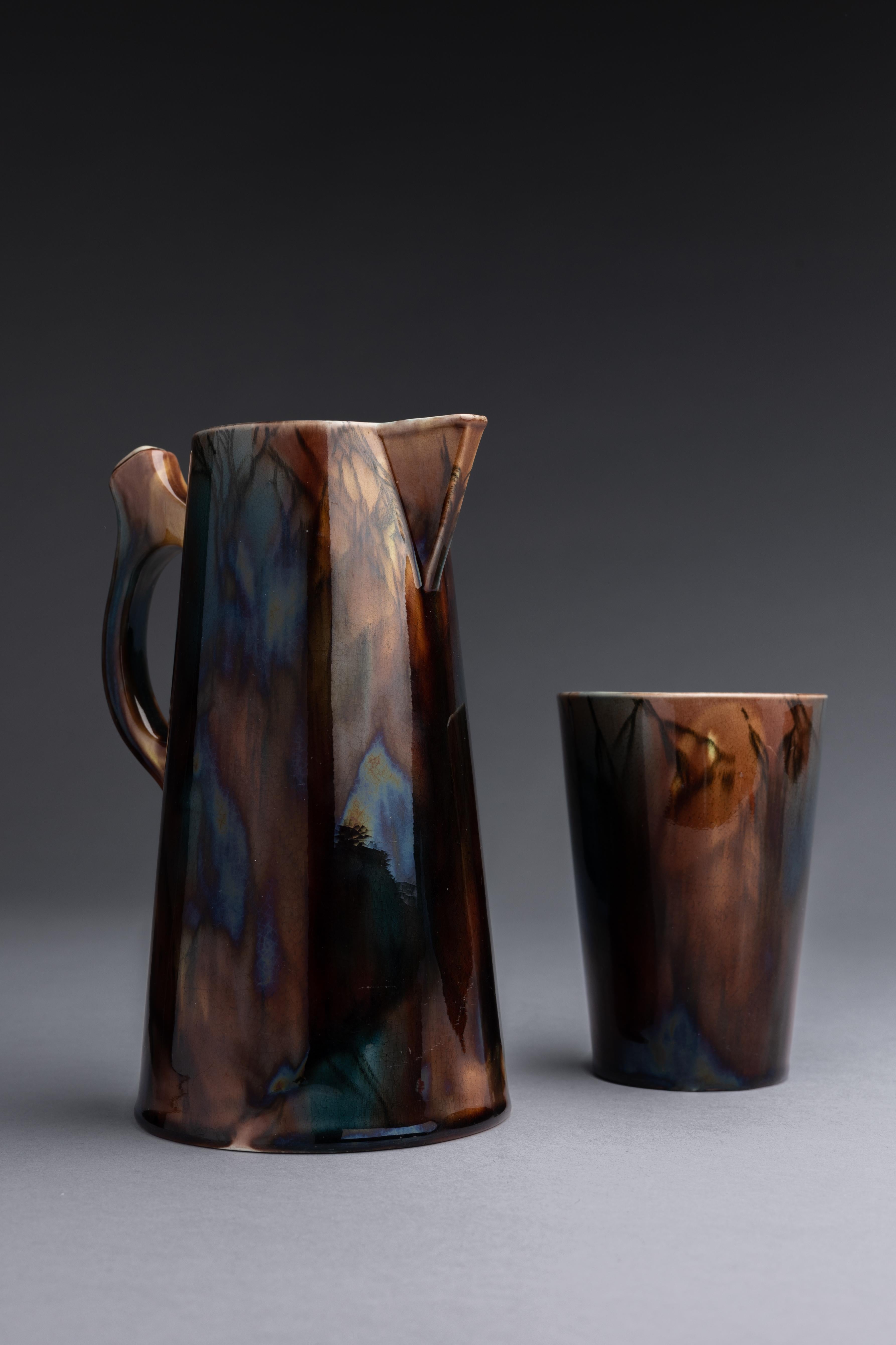 Un juego de jarra y vaso de Wedgwood con una rara coloración de mayólica de marrón moteado con un toque de azul cobalto.

Esta jarra y este vaso, diseñados por Wedgwood en 1877, son un ejemplo único de cerámica mayólica. La mayoría de las piezas