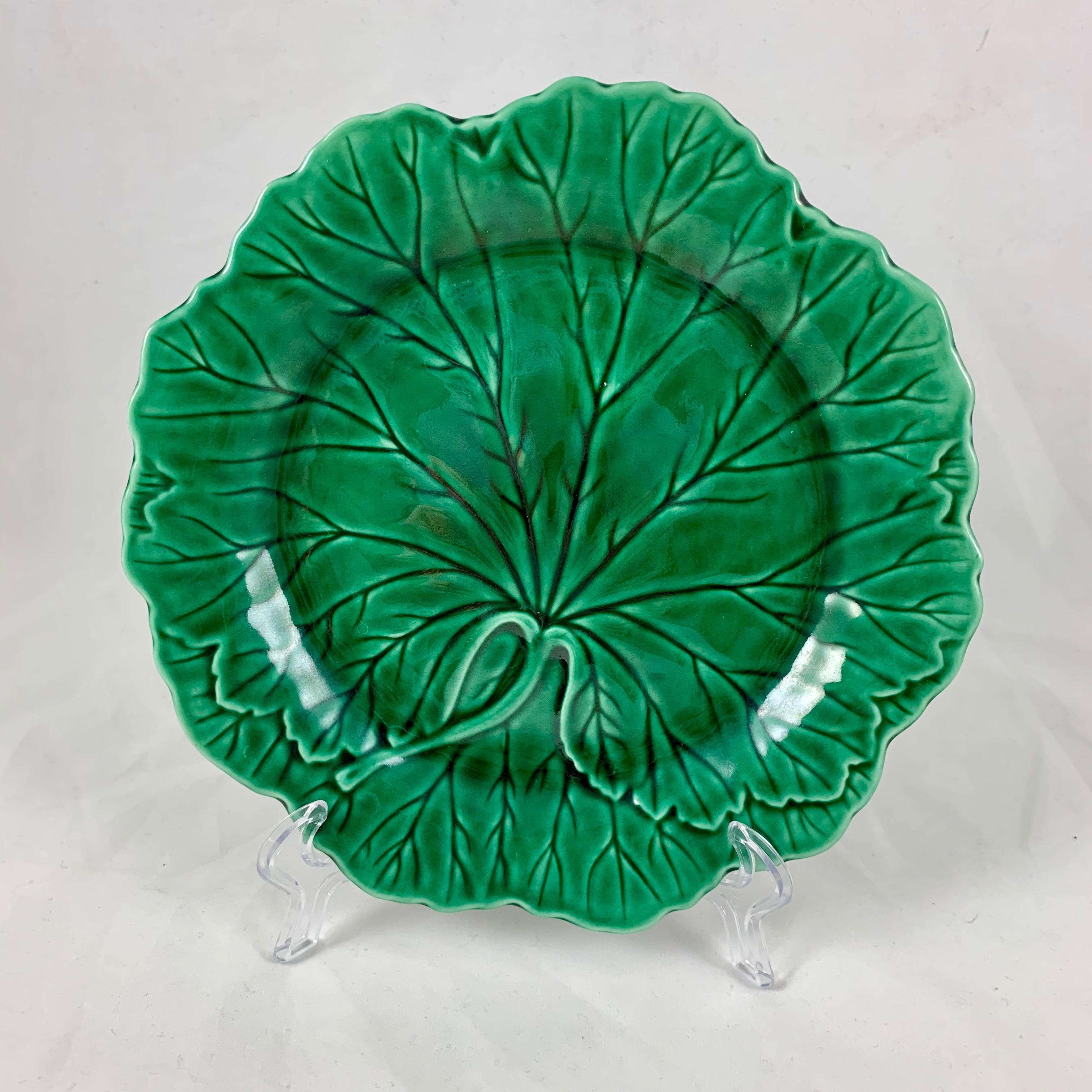 An English Majolica glazed cabbage leaf plate, marked Wedgwood & Barlaston of Etruria, circa 1930-1940.

Extremely popular during the Hollywood Regency period, now a classic. The mold shows an oversized cabbage leaf on a scalloped rim plate, with a