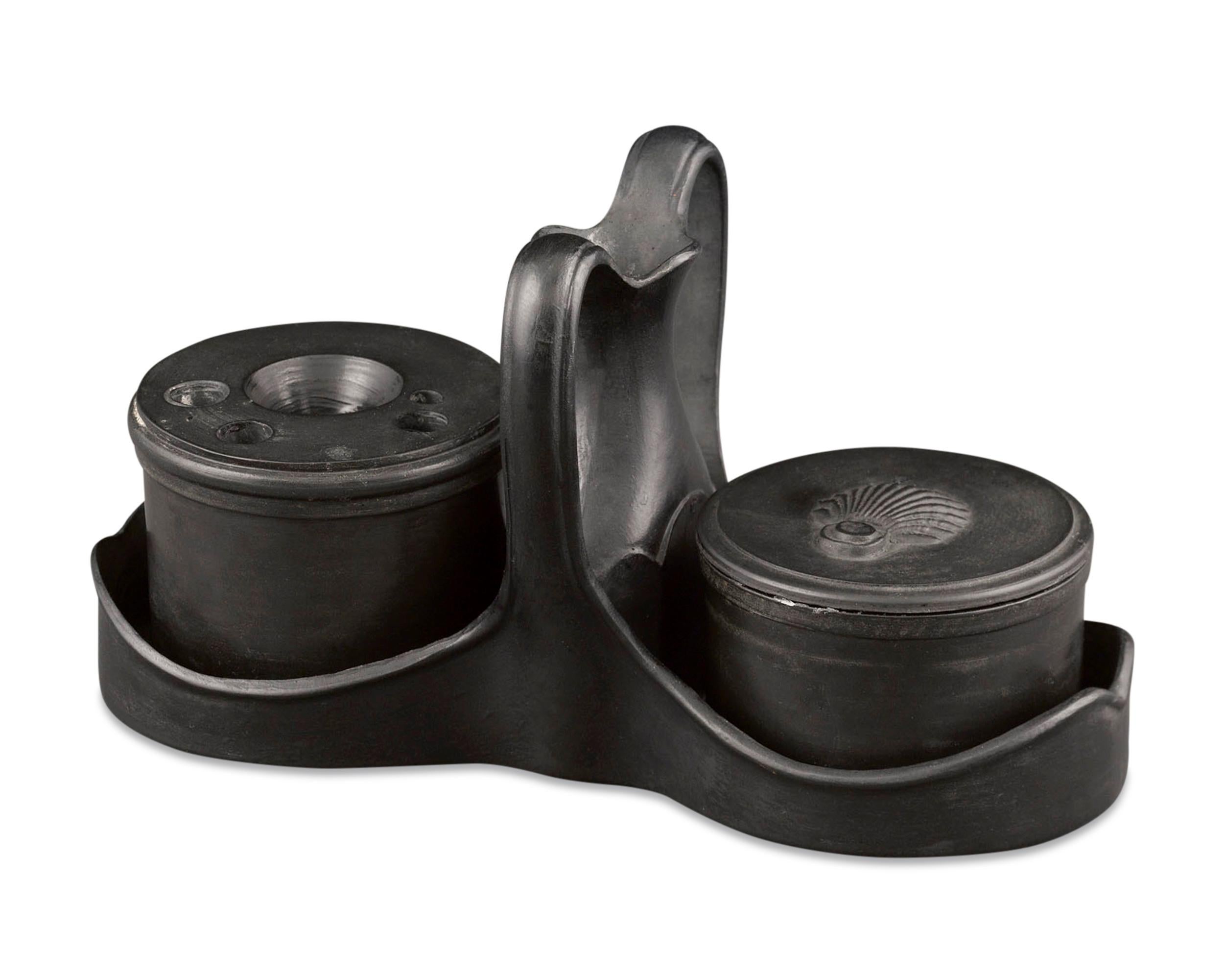 This elegant inkwell set by Wedgwood & Bentley is crafted of black basalt, one of Wedgwood’s finest inventions. The set is comprised of two canisters, both held within an intriguing double stand. One is designed to hold ink and features a top with