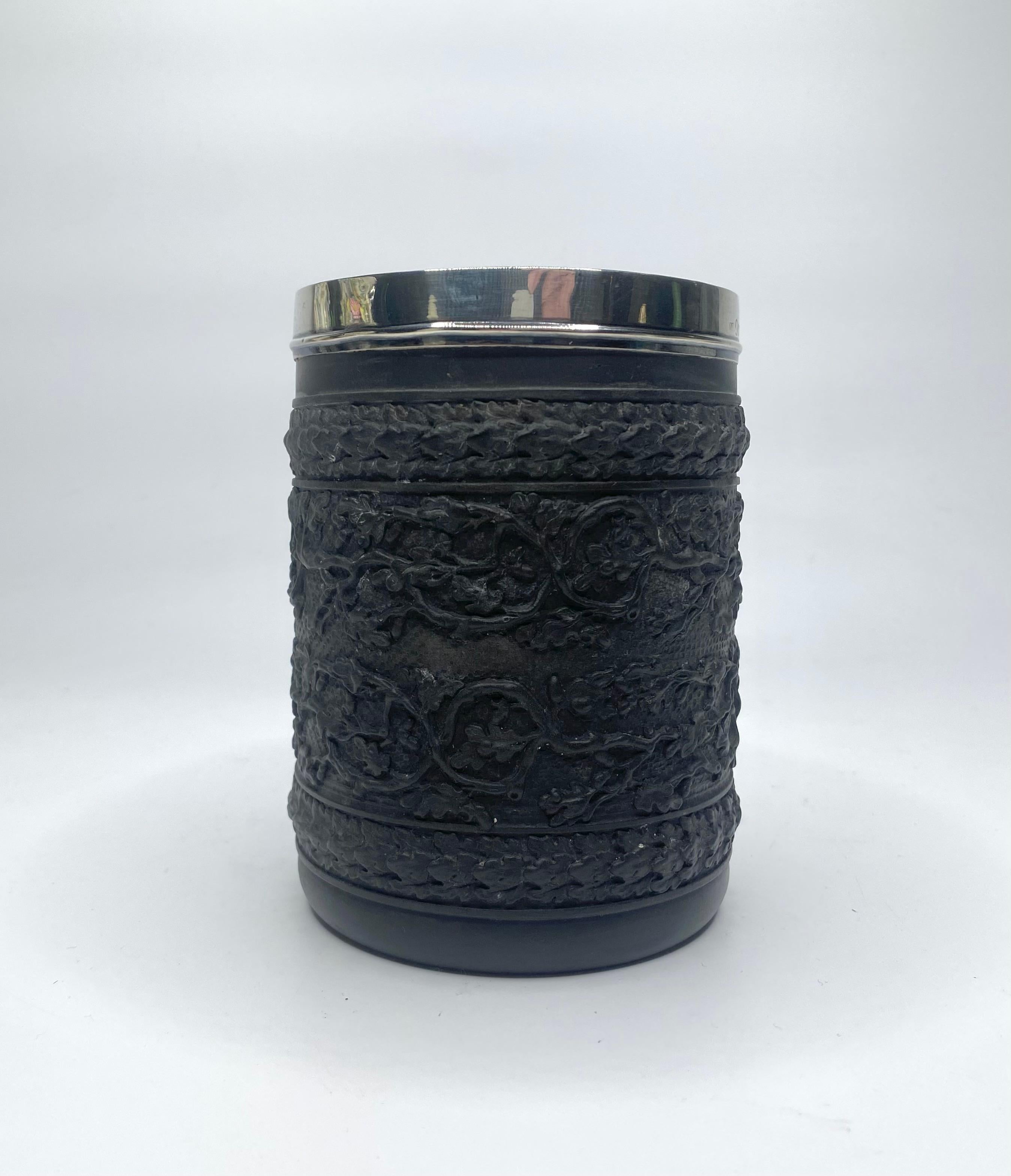 Wedgwood black basalt mug, with silver mount, dated 1808. The mug heavily moulded with a continuous band of entwined branches of oak leaves and acorns, between bands of overlapping leaves. The loop handle moulded with overlapping leaves.
Silver