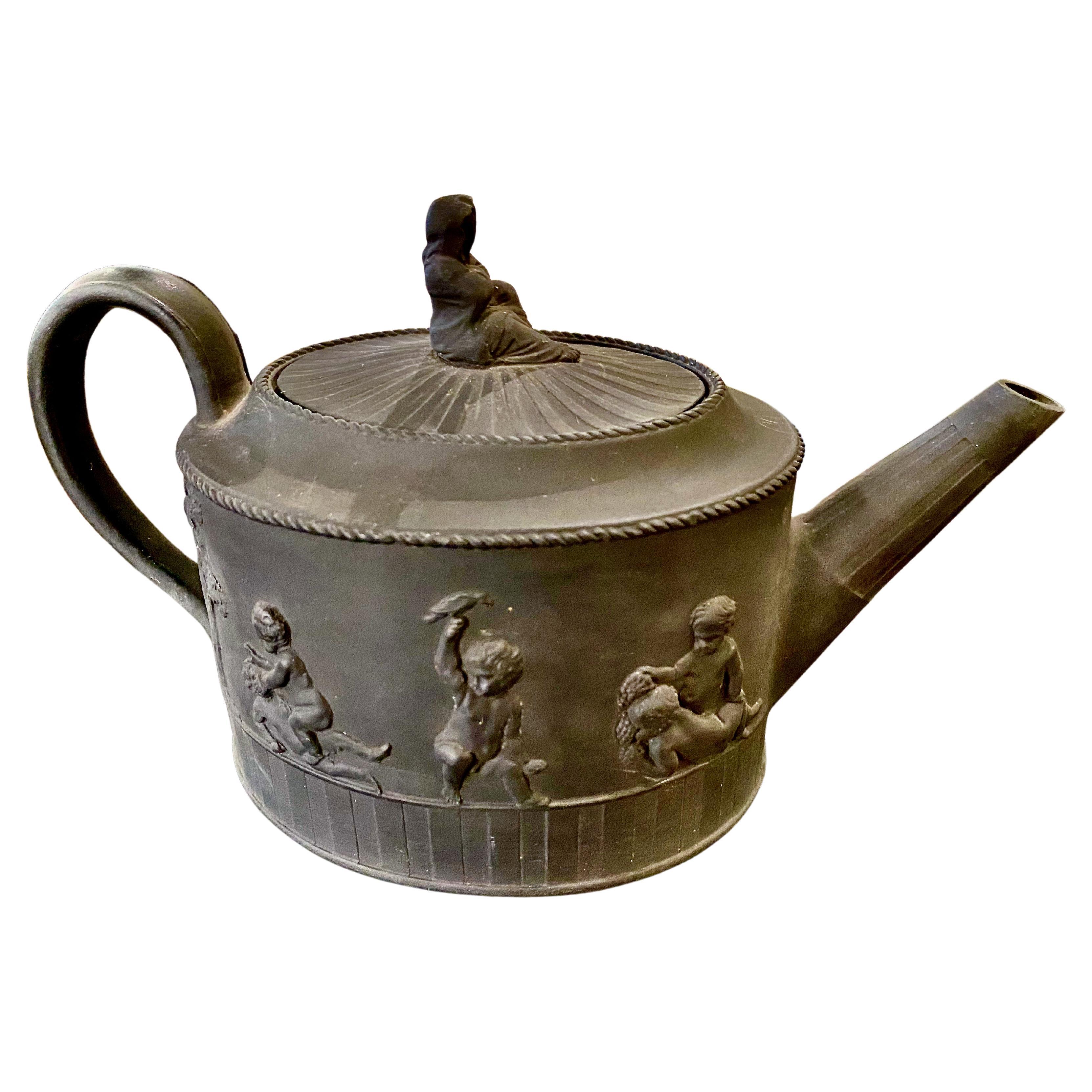 This is a very good example of a Wedgwood (signed) late 18th century Black Basalt Teapot. The Teapot is in overall very good condition and features a band of putti ringing the body of the pot; engine turning at the base and a figural finial.