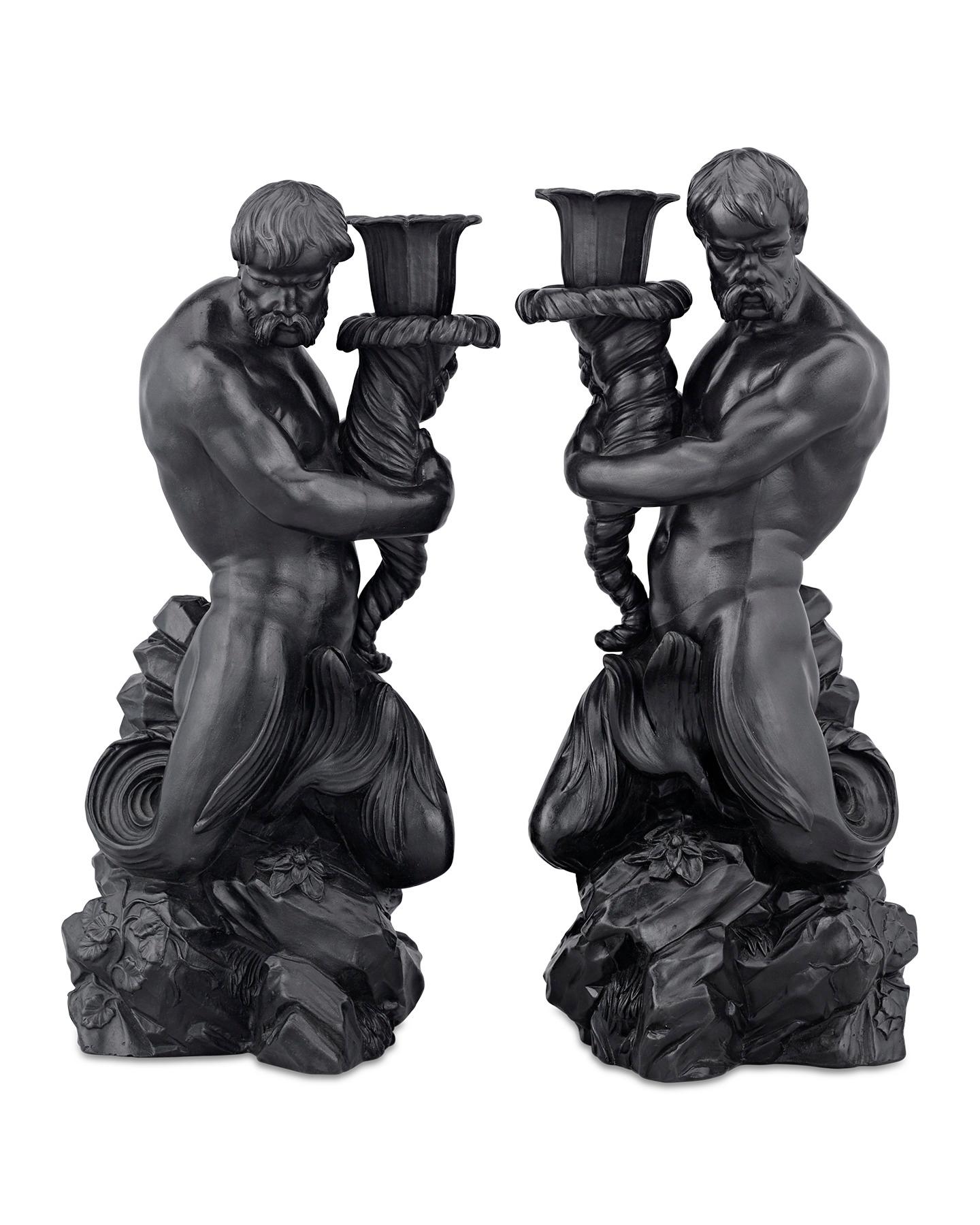 Designed by Wedgwood, this majestic pair of candlesticks is crafted from the English ceramic firm’s famous black basalt stoneware. Two identical glossy figures take the form of Triton, a Greek god of the sea in Classical myth, represented as a