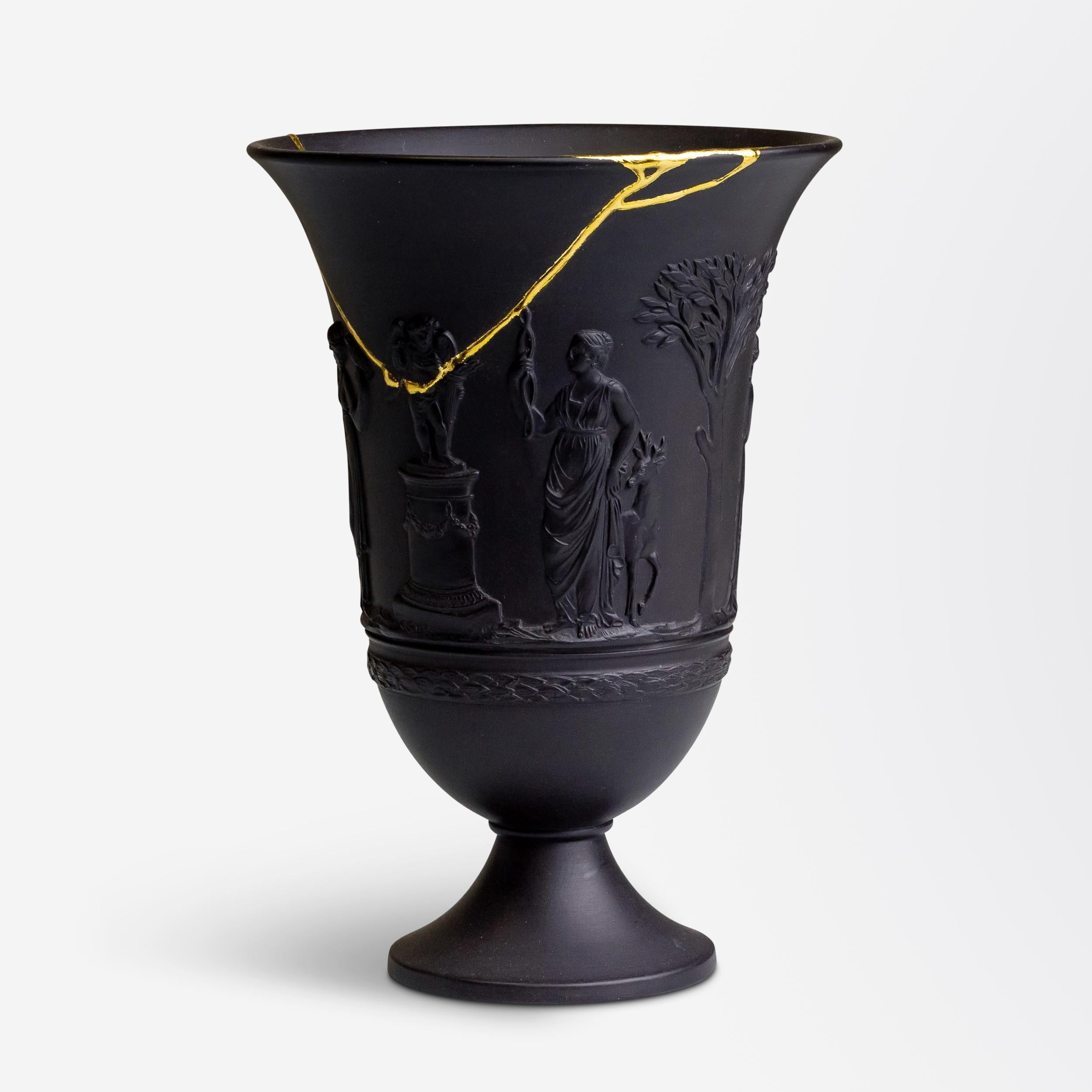 With its unique kintsugi style repair, this Wedgwood black basalt vase has become one of a kind. The flared trumpet style vase was made by Wedgwood in the first half of the 20th century, circa 1930 and depicts classical figures in relief around the