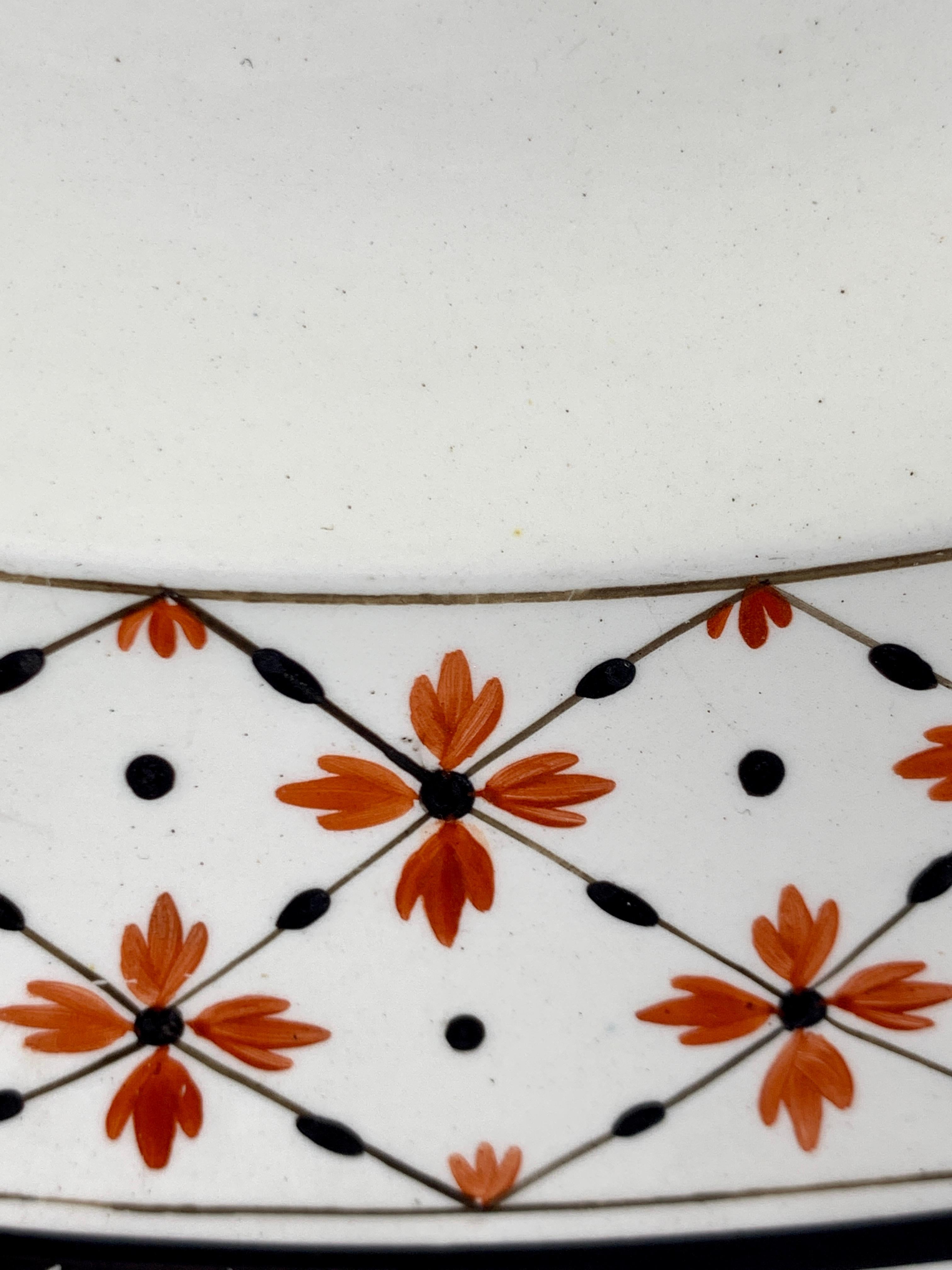 Ce plat rond ou chargeur en creamware de Wedgwood a été fabriqué au XVIIIe siècle en Angleterre, vers 1785.
La bordure est décorée d'un motif néoclassique traditionnel de têtes de fleurs rouge fer reliées par des 