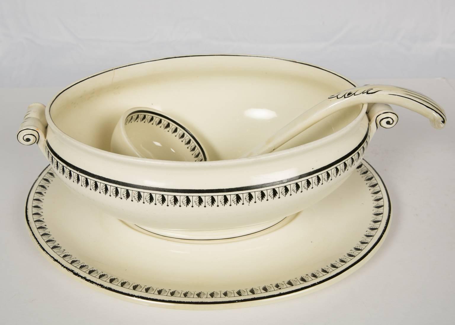 This elegant 19th century Wedgwood creamware soup tureen is modeled in an elegant oval shape. It is decorated with a neoclassical black leaf and dot design along both the border of the tureen and the cover. Surrounding the flower finial on the cover