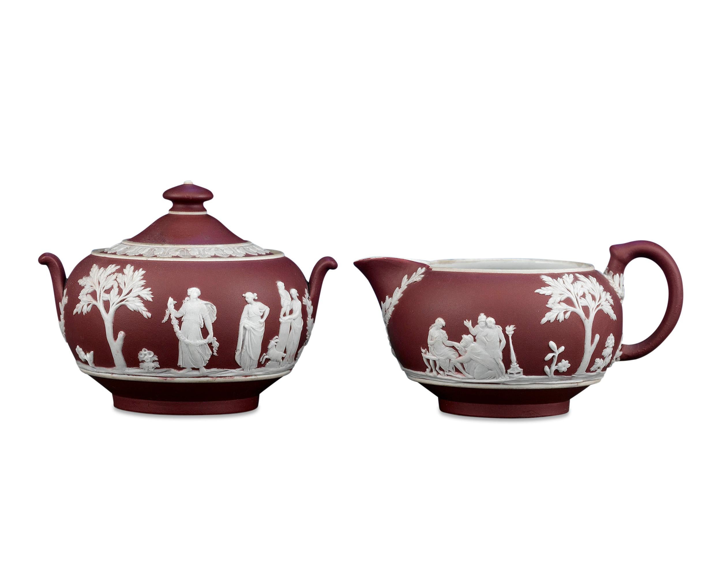 This beautiful jasper dip creamer and sugar bowl set is the work of the famed Wedgwood and exhibits the company's rare crimson hue. Crafted in the classical taste, both pieces in this elegant set are adorned with white classical figures applied in