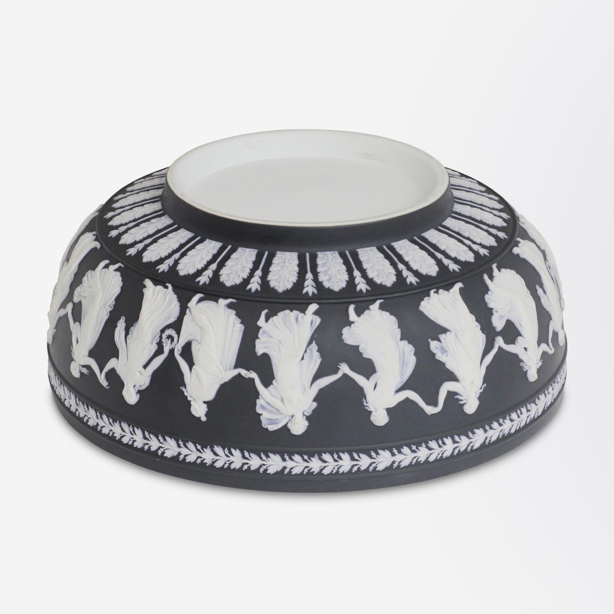 A fine black jasper-ware bowl crafted by Wedgwood in a design known as the 'Dancing Hours'. The black basalt wash over white jasper piece dates to the 1950s and has been handmade in England. The design dates to the 18th century by John Flaxman
