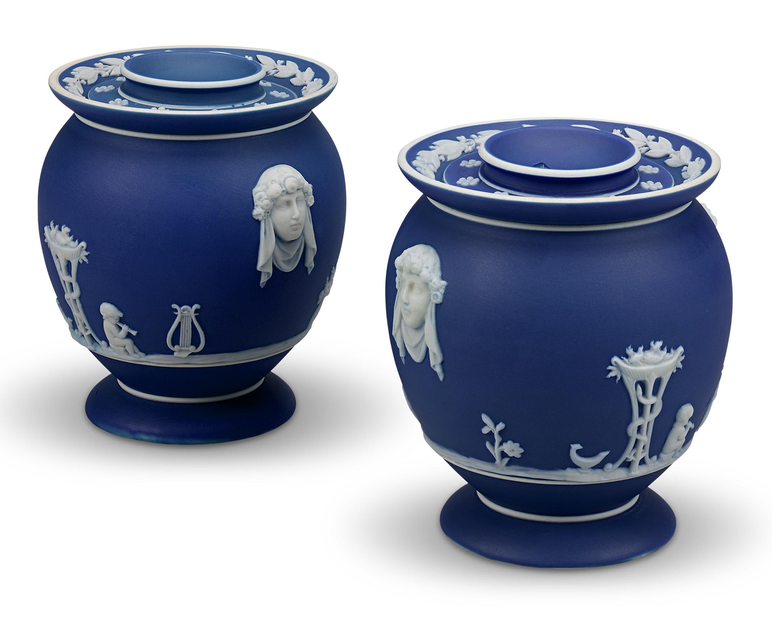 Timeless and elegant, this pair of Wedgwood fumigator jars is crafted of the firm’s signature jasperware. This pair of vessels showcases a striking deep blue hue, contrasting greatly with the classical figures rendered in relief on their surface.