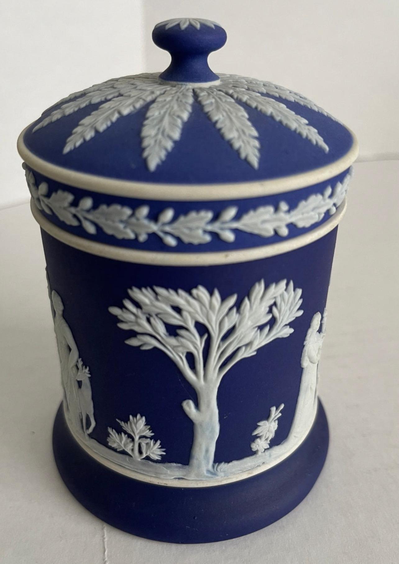 Wedgwood dark blue Jasperware tobacco jar. Overall white neoclassical motif. Light overall age related wear. No chips or repairs. 
Stamped Wedgwood Made in England on the underside.