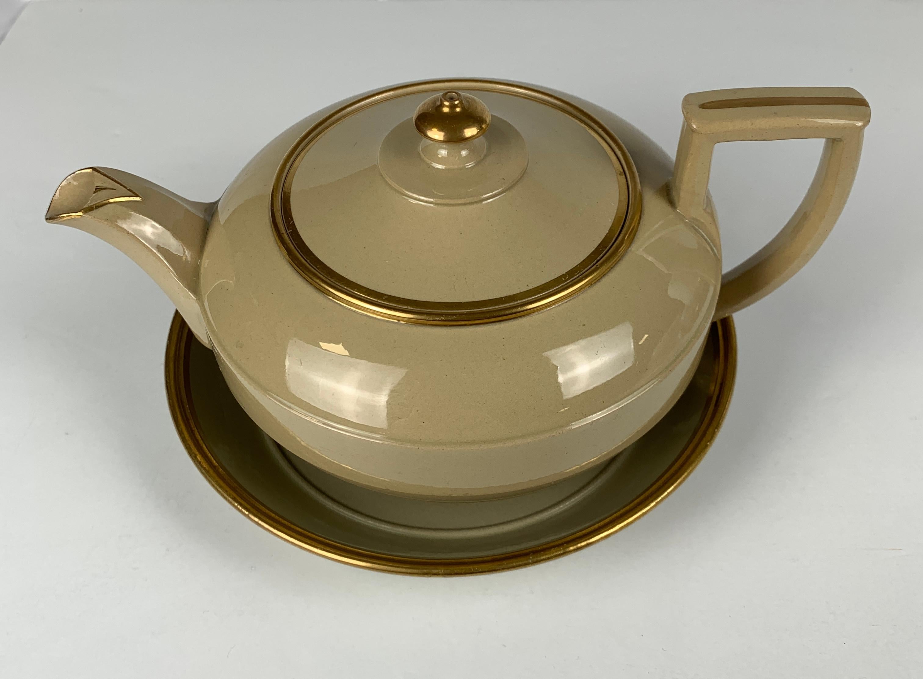 Wedgwood made this drabware teapot and stand in Staffordshire, England, in the first quarter of the 19th century, circa 1825.
The design is simple and elegant, and the decoration is minimal, with only a bit of gilt trim accentuating the